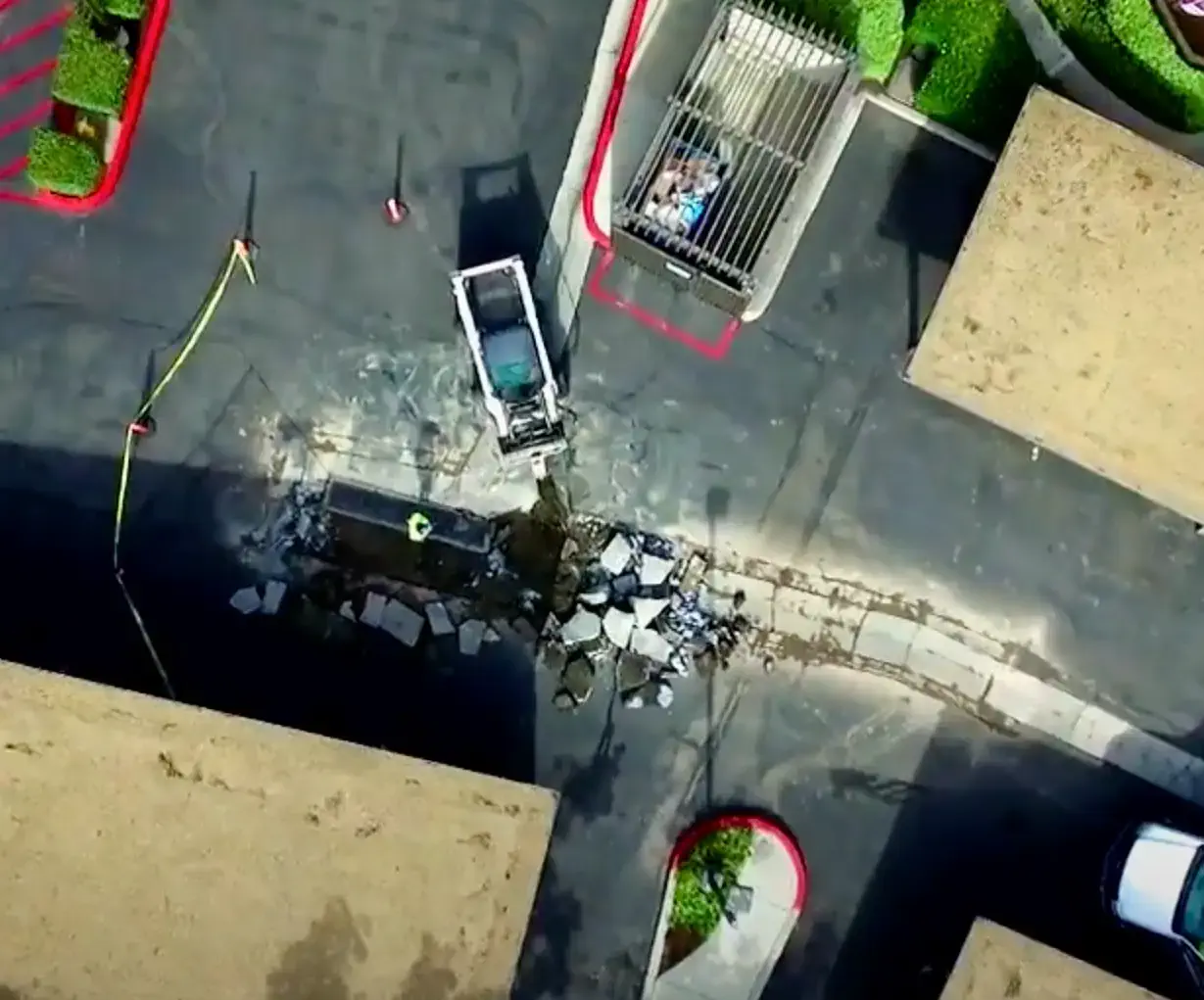 Demolición de concreto con accesorio de barrena para minicargadora en un proyecto de concreto en un complejo de apartamentos