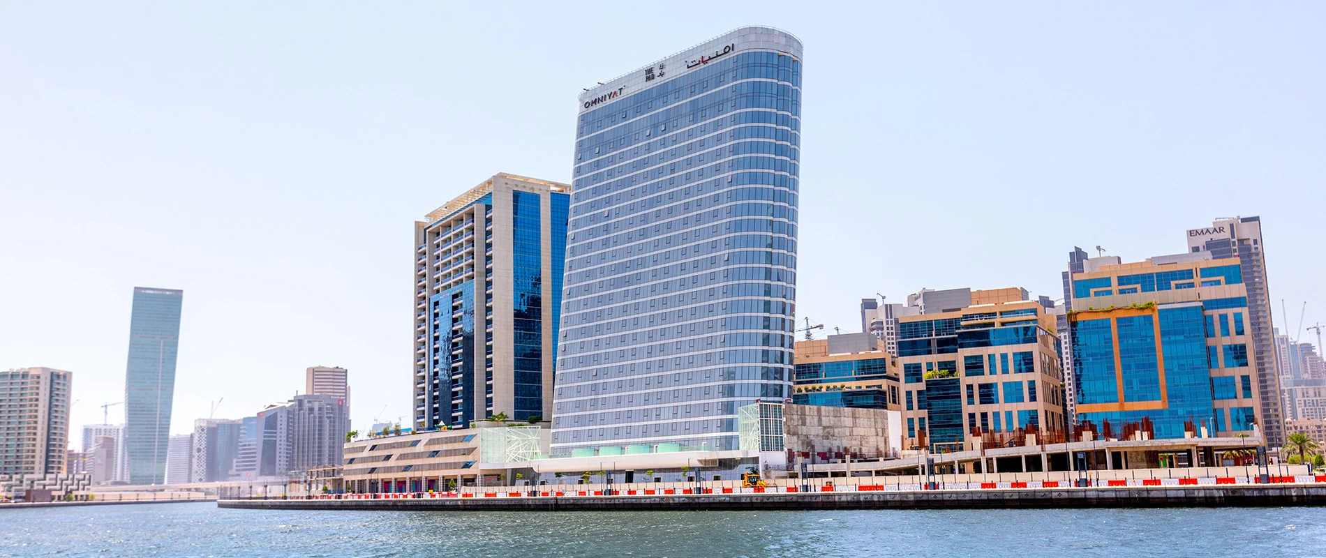  large building with tall glass windows surrounded by palm trees, known as The Pad by OMNIYAT.