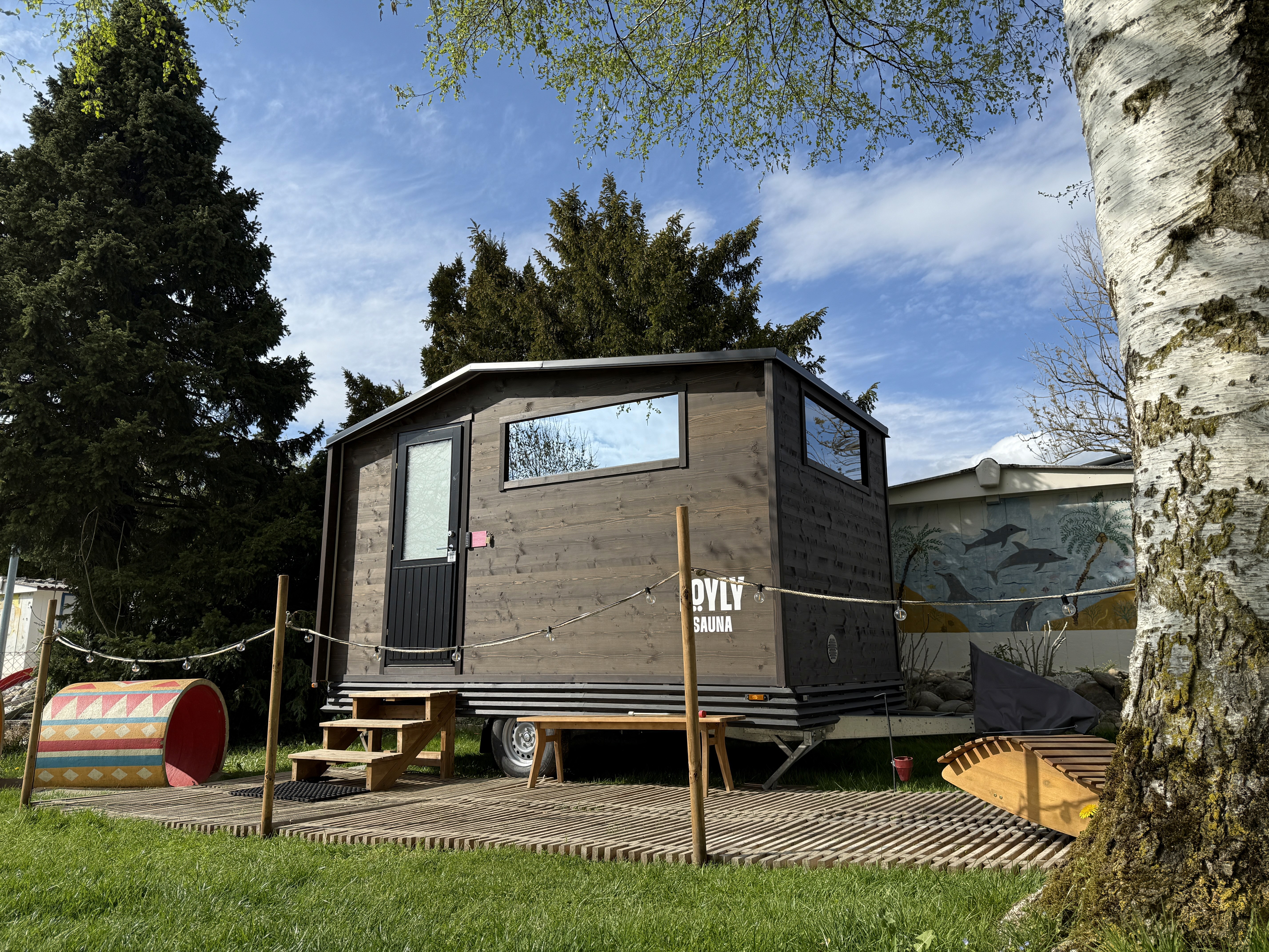 Mobile LÖYLY-Sauna im Strandbad Männedorf, eingebettet zwischen Bäumen und Natur für Sauna- und Wellness-Erlebnisse am Zürichsee.