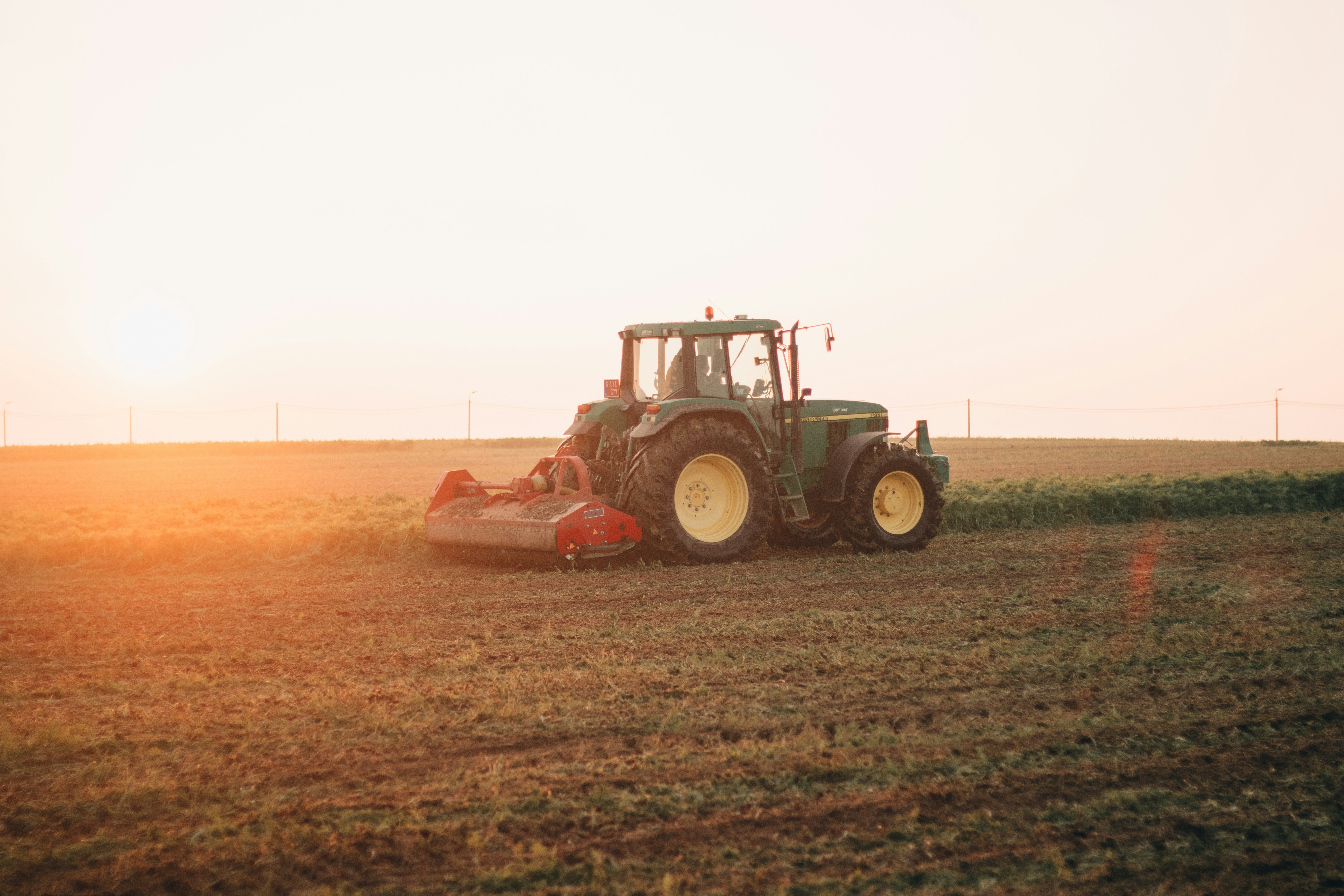 Tractor equipped with precision agriculture technology working a field at sunset