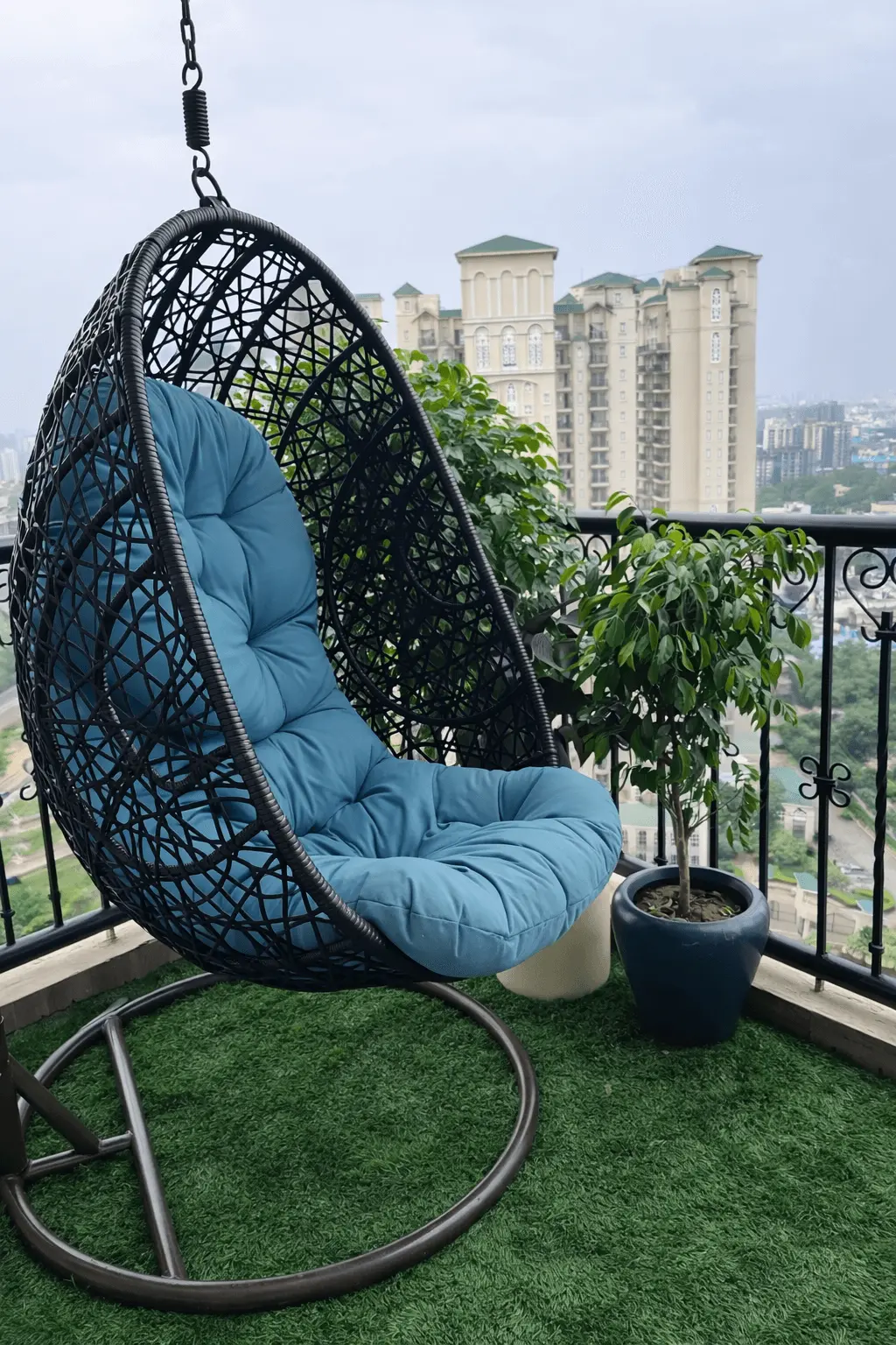 Iron hanging swing chair with a stand on a city balcony