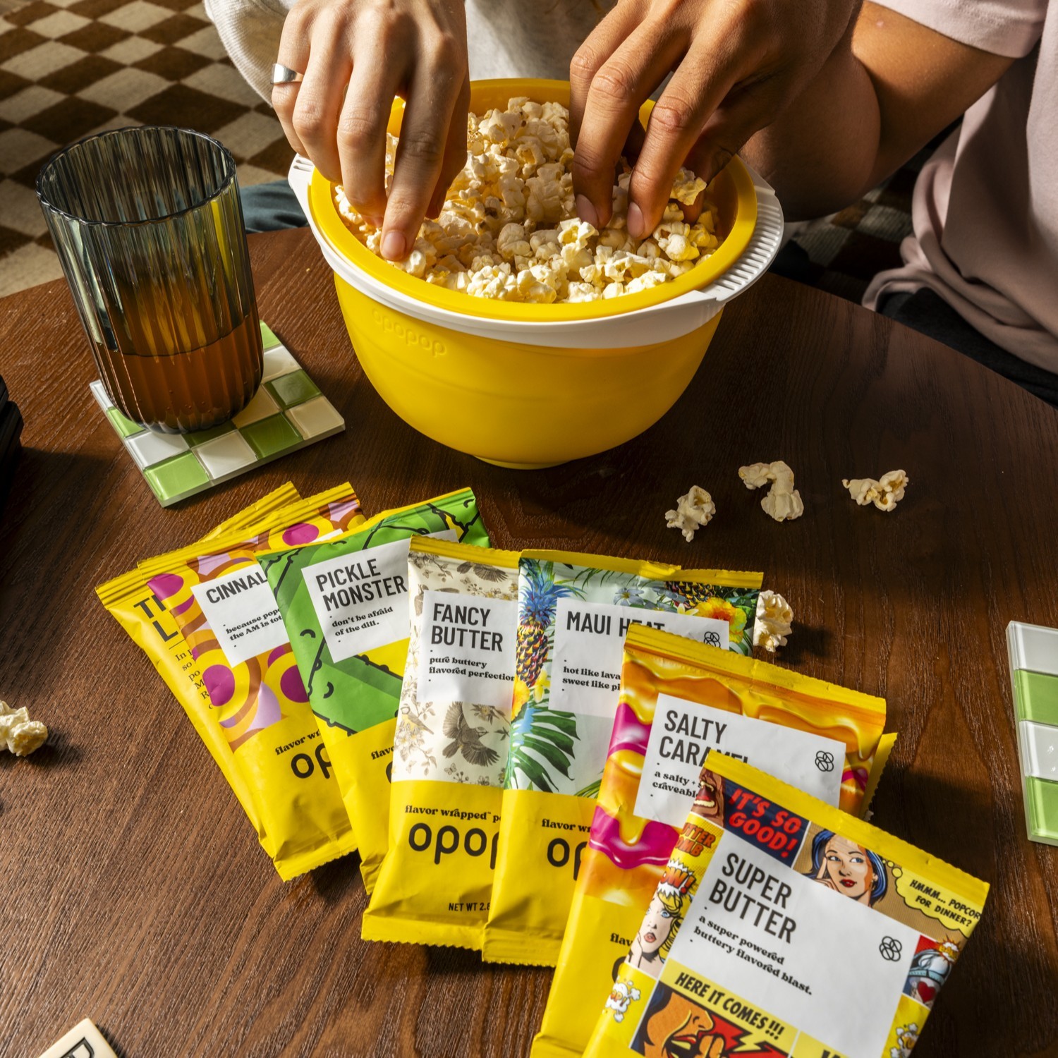 Hands sharing popcorn from a yellow Opopop bowl