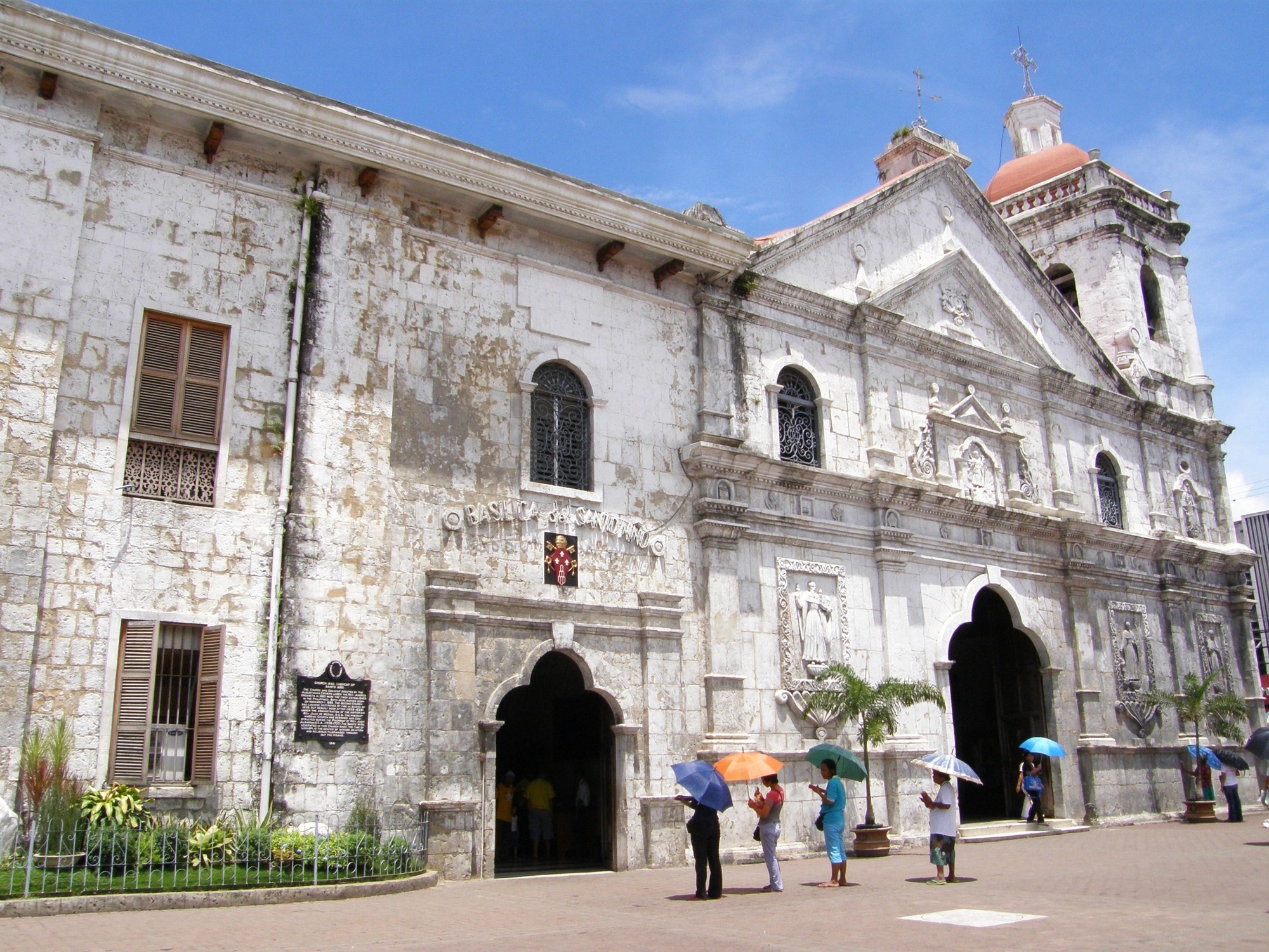 a street lined with stone buildings next to a lush green forest