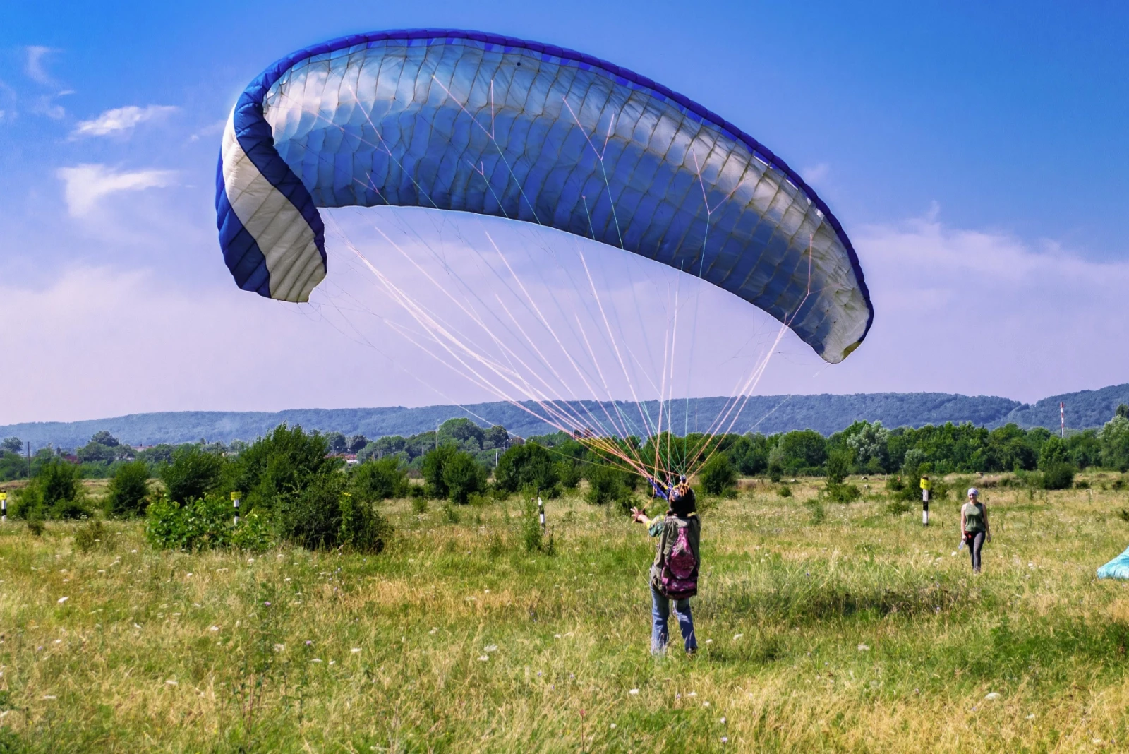 Two people in casual attire sail a small boat on a city waterfront. They focus on steering, with modern buildings in the background and a relaxed atmosphere. Photo by Михаил Таврионов