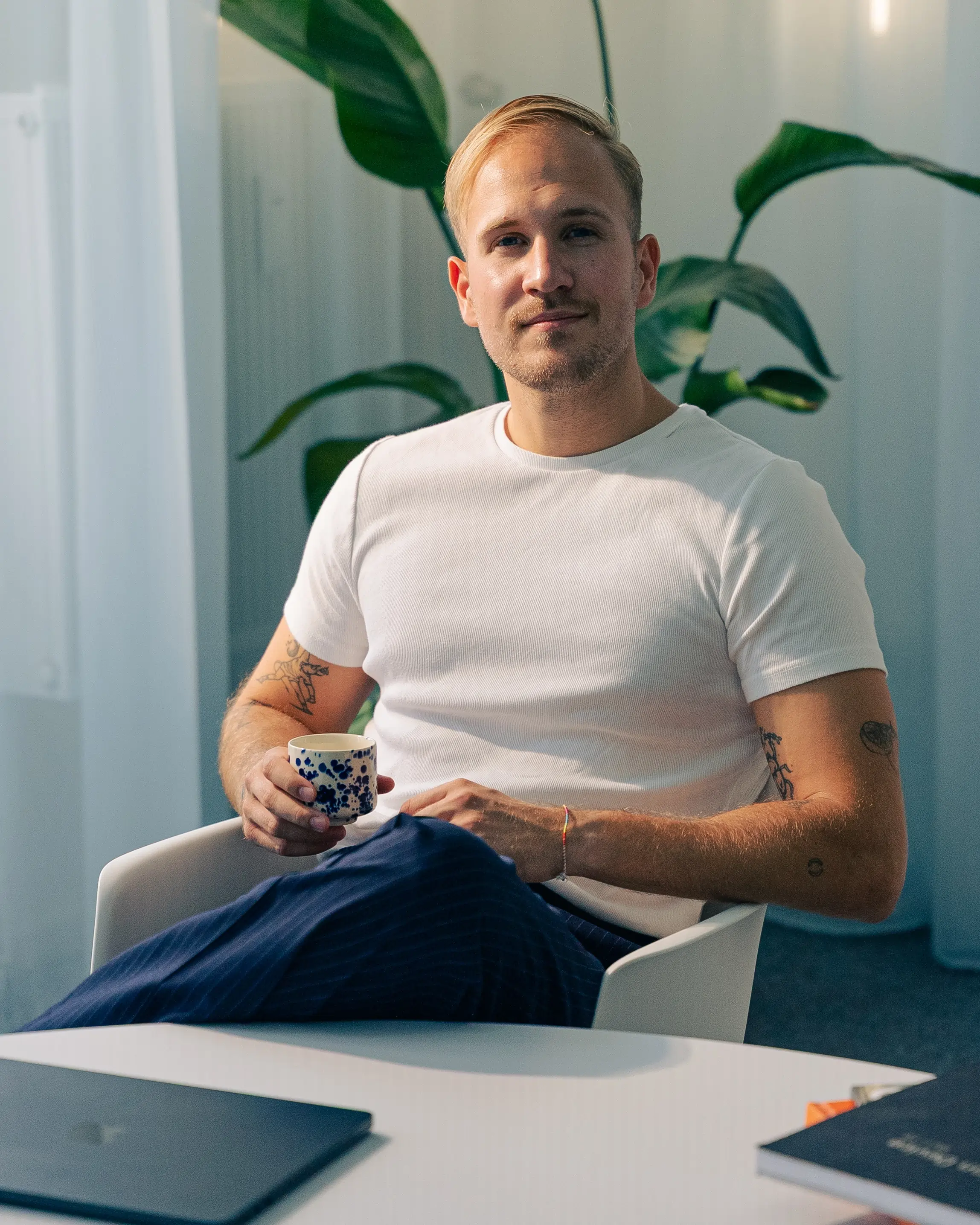 Mature man with glasses and a trimmed beard smiling confidently, standing in warm natural light against a modern backdrop.