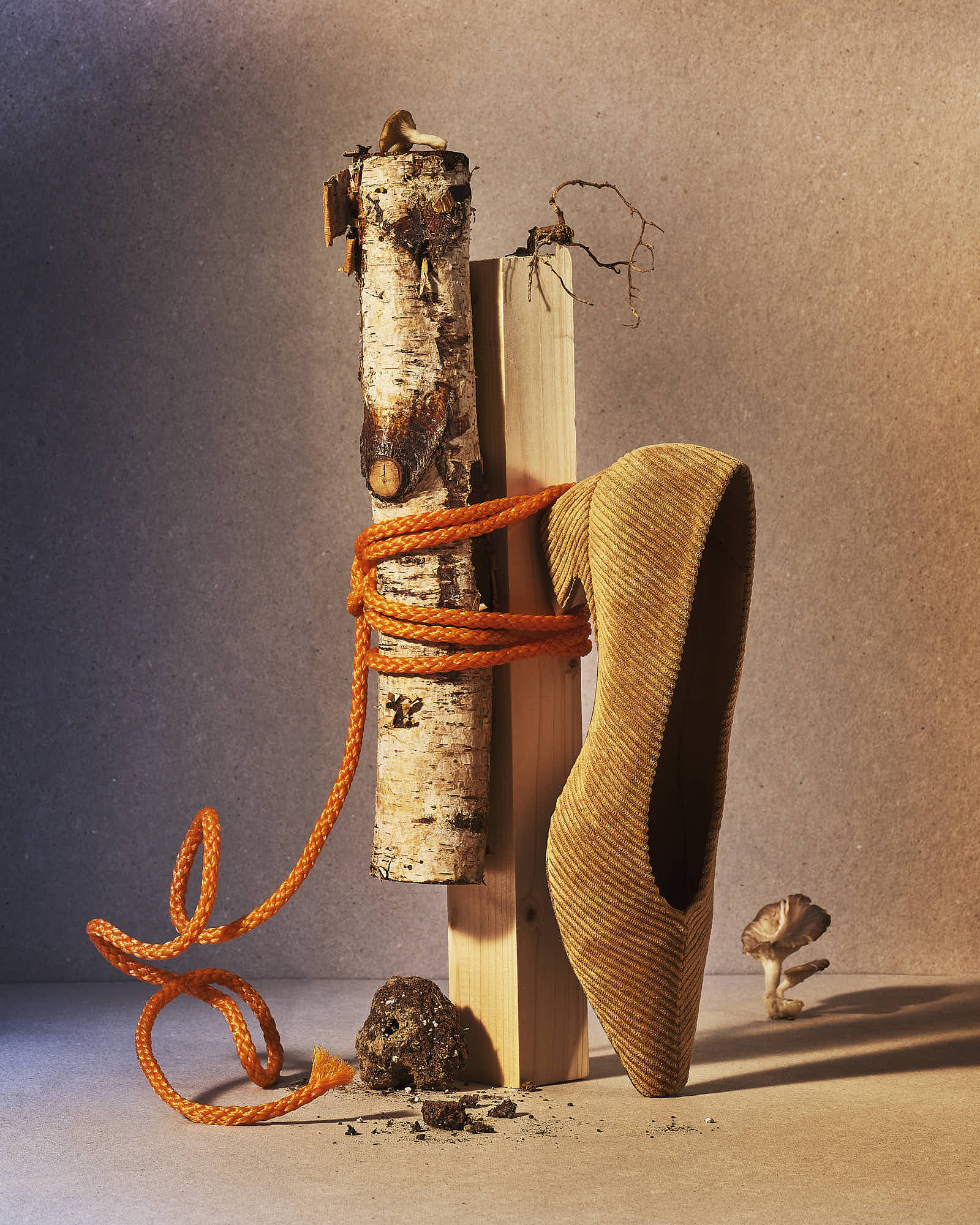 Creative still life with orange rope, wood, and a corduroy shoe on a neutral background.