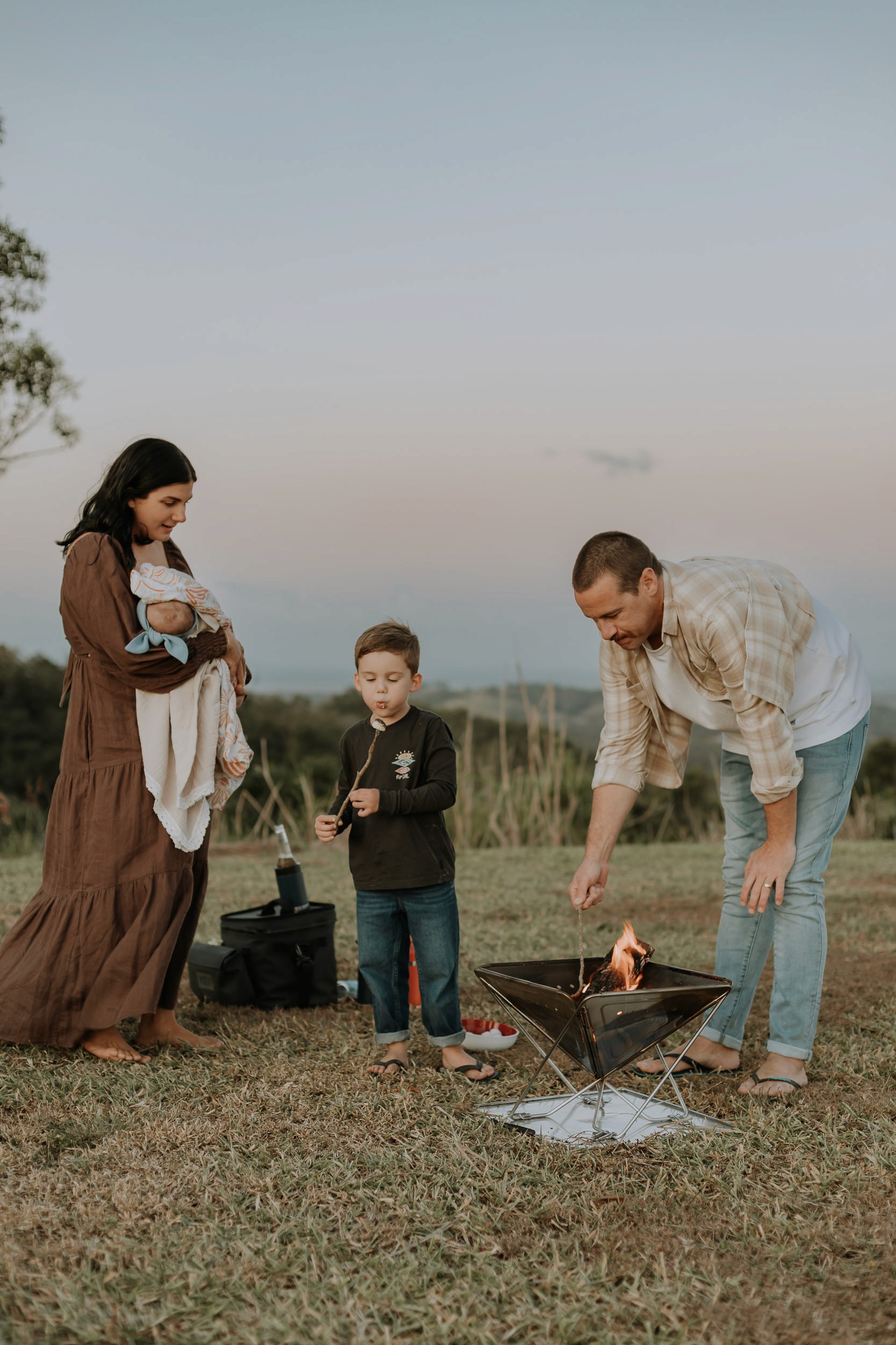 Family toasting marshmallows around the fire at home photoshoot in Mackay