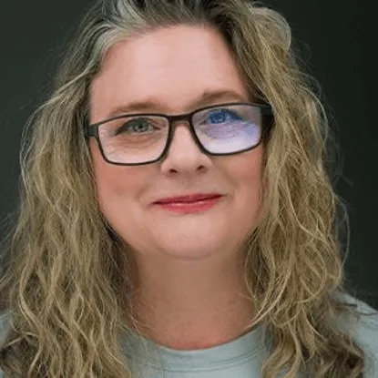 Woman with glasses and wavy blonde hair smiles
