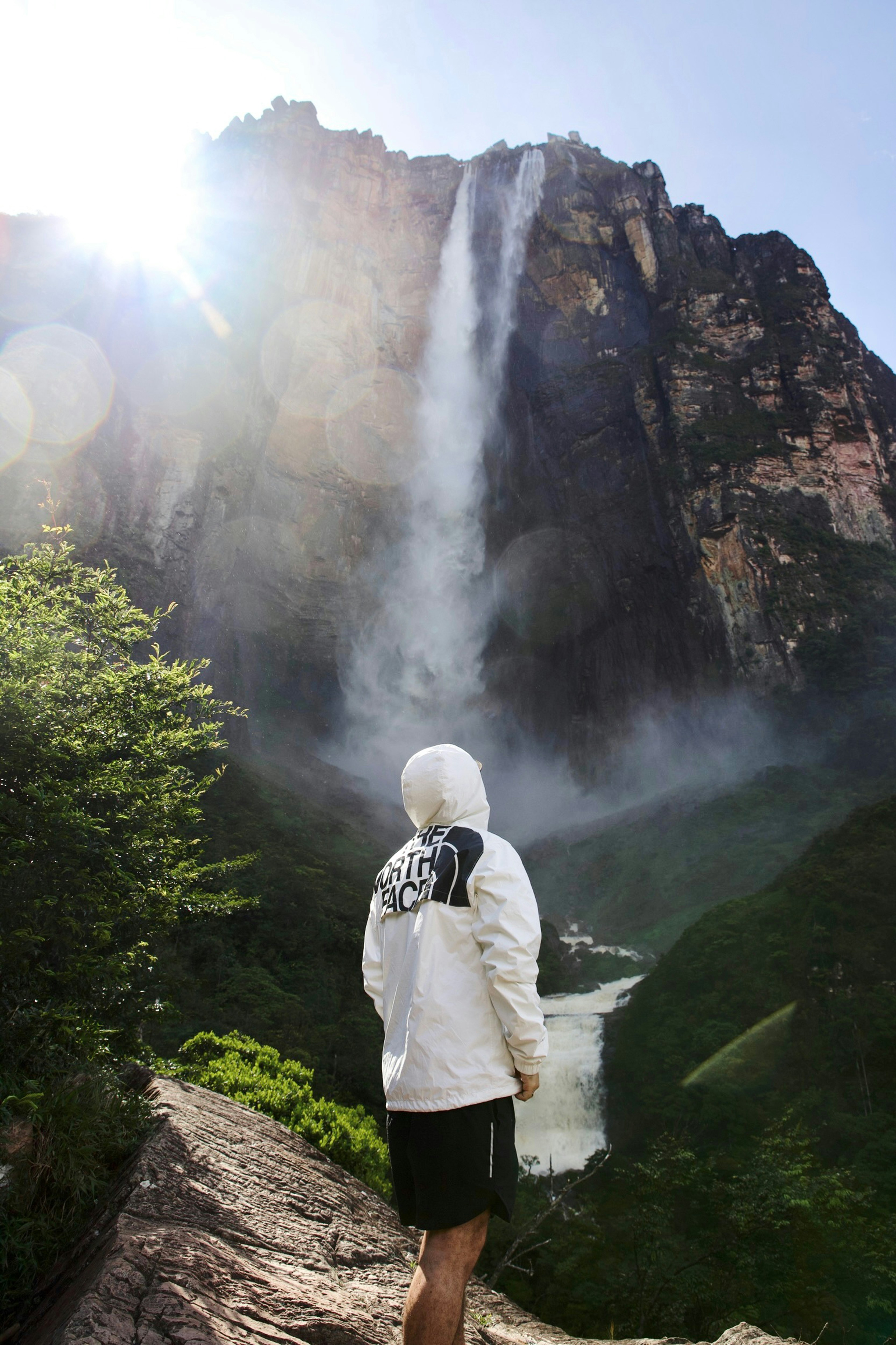 a man standing before a waterfall