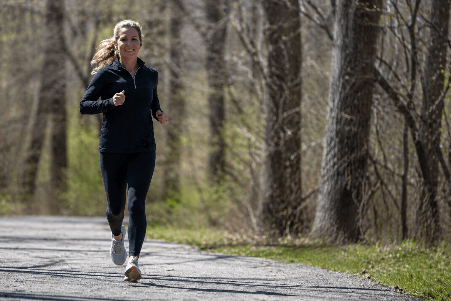 A person jogging on a pathway surrounded by trees in a natural setting.