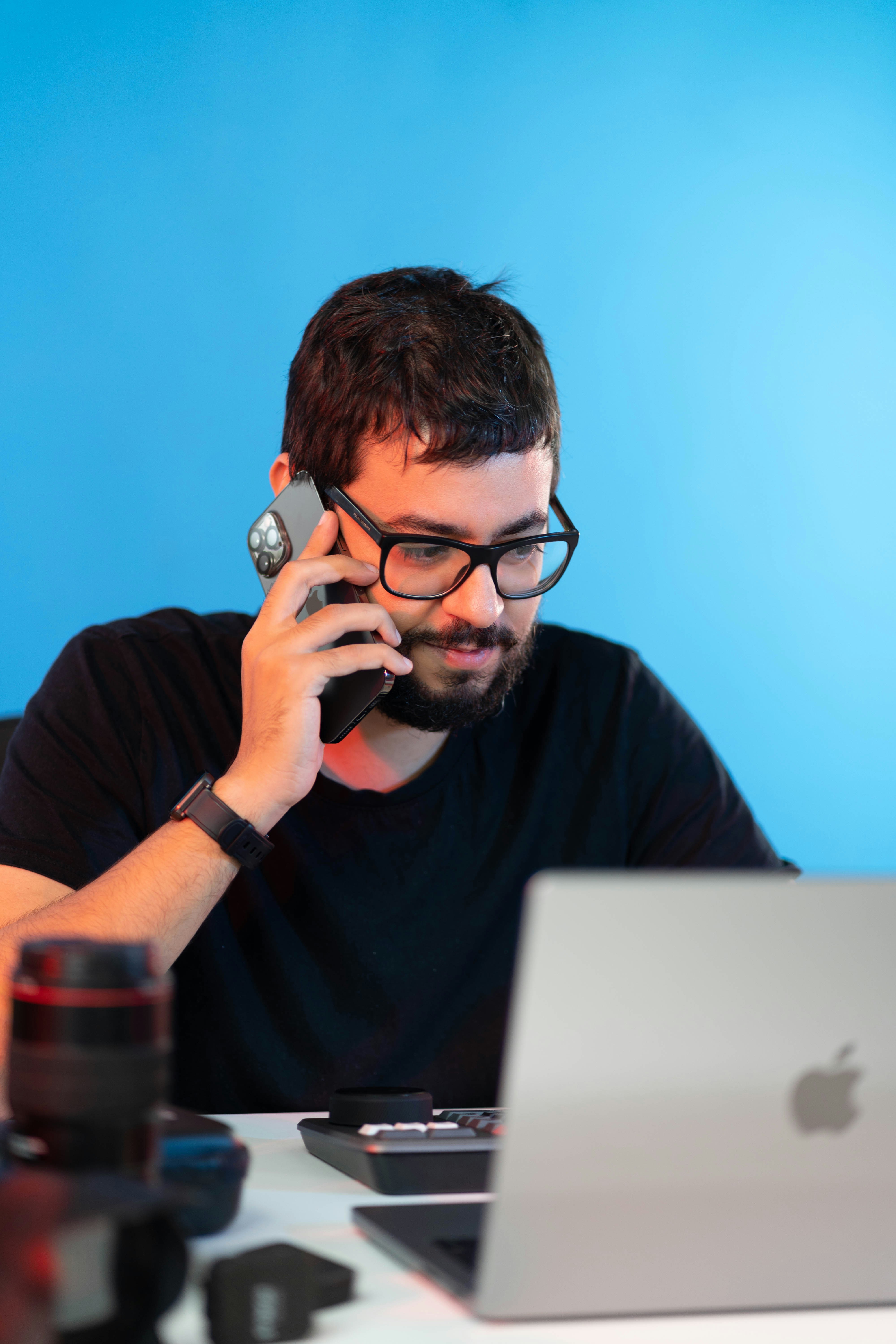 a man sitting at a desk talking on a cell phone