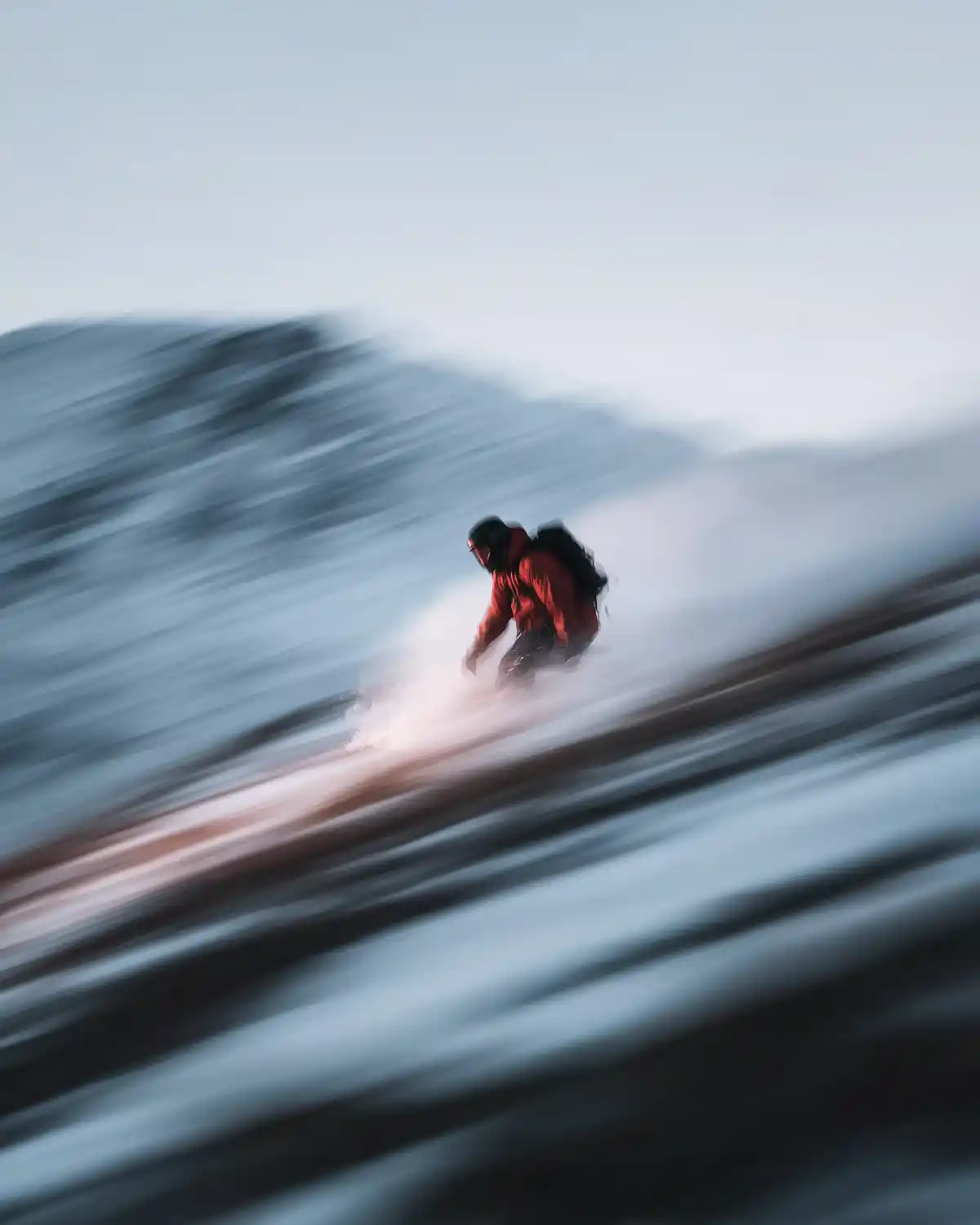 A cyclist in motion, wearing a white jersey and helmet, rides a sleek black bike with orange accents against a blurred urban backdrop.