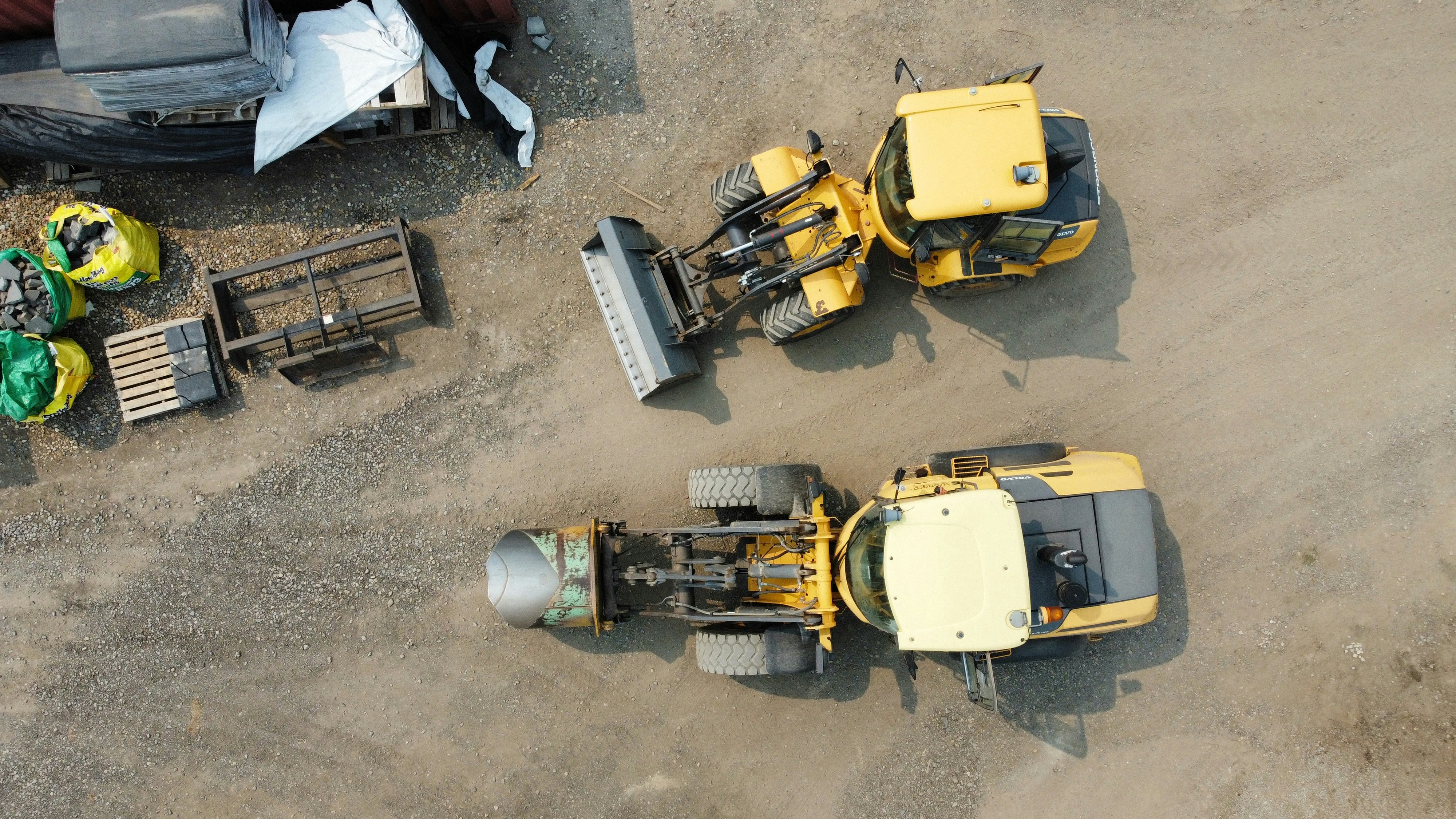 Two yellow construction vehicles parked on gravel