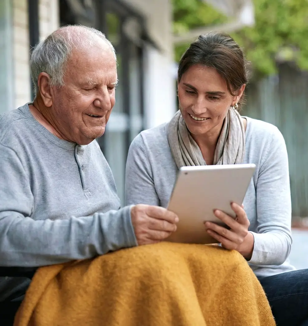 Caregiver and senior client looking at a tablet together during an evening at-home visit