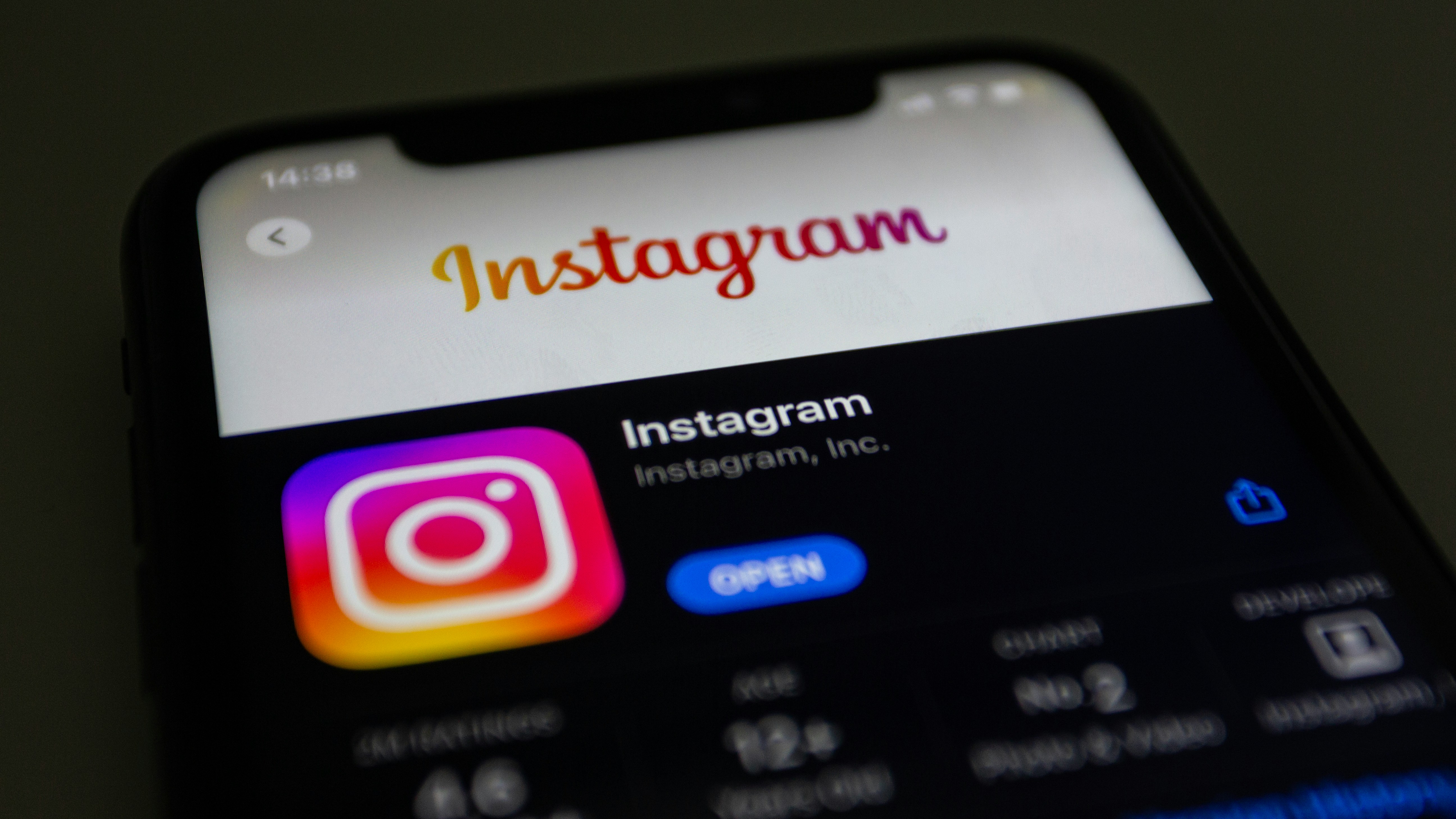 A phone screen displays the Instagram app on the App Store, featuring the Instagram logo prominently, with other elements like ratings and age restrictions blurred.