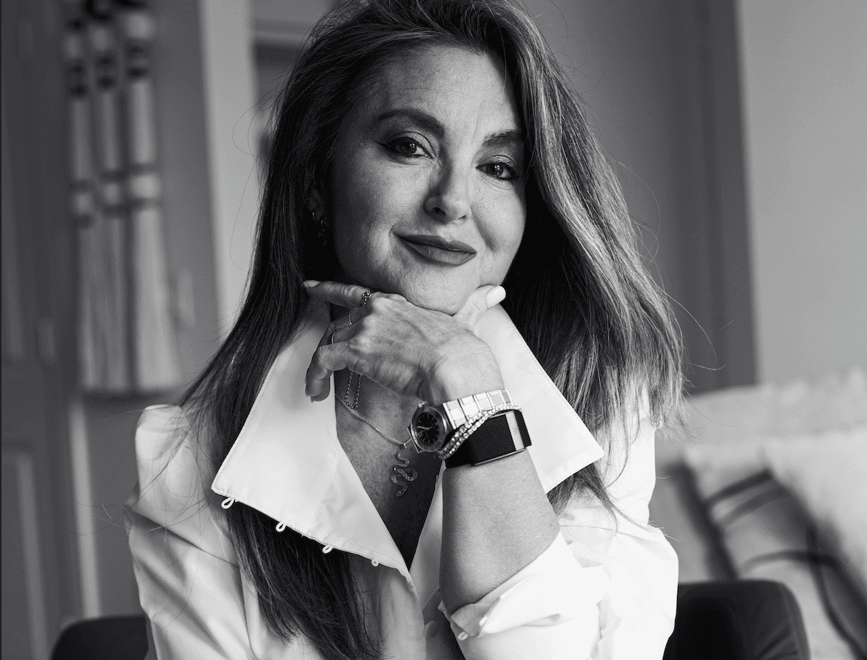 Young woman with shoulder-length dark hair wearing a pink collared shirt, looking directly at camera
