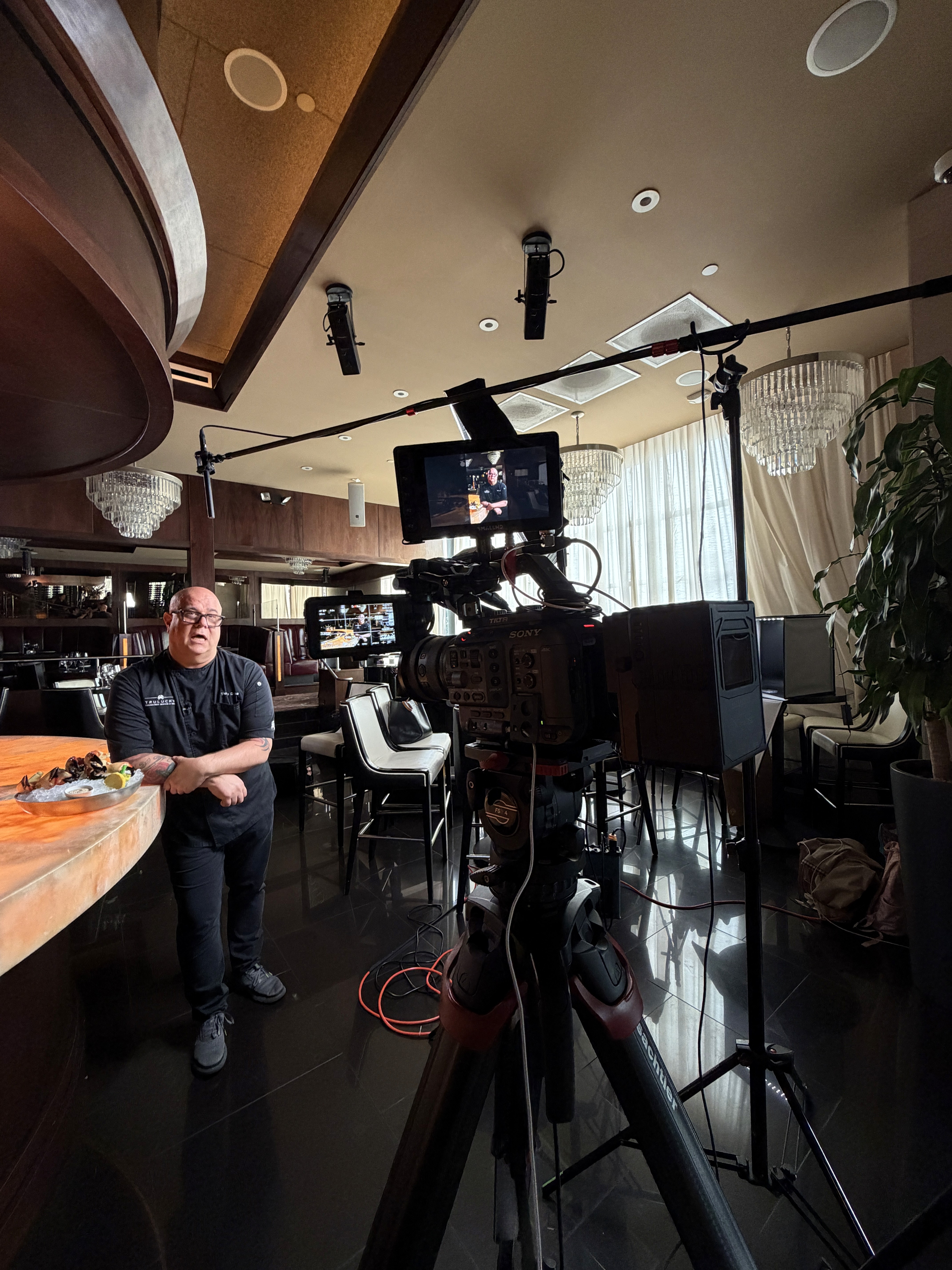 Black and white image of people working at a table with laptops, showing hands gesturing during discussion of digital content displayed on screens, with fabrica® logo in the corner.
