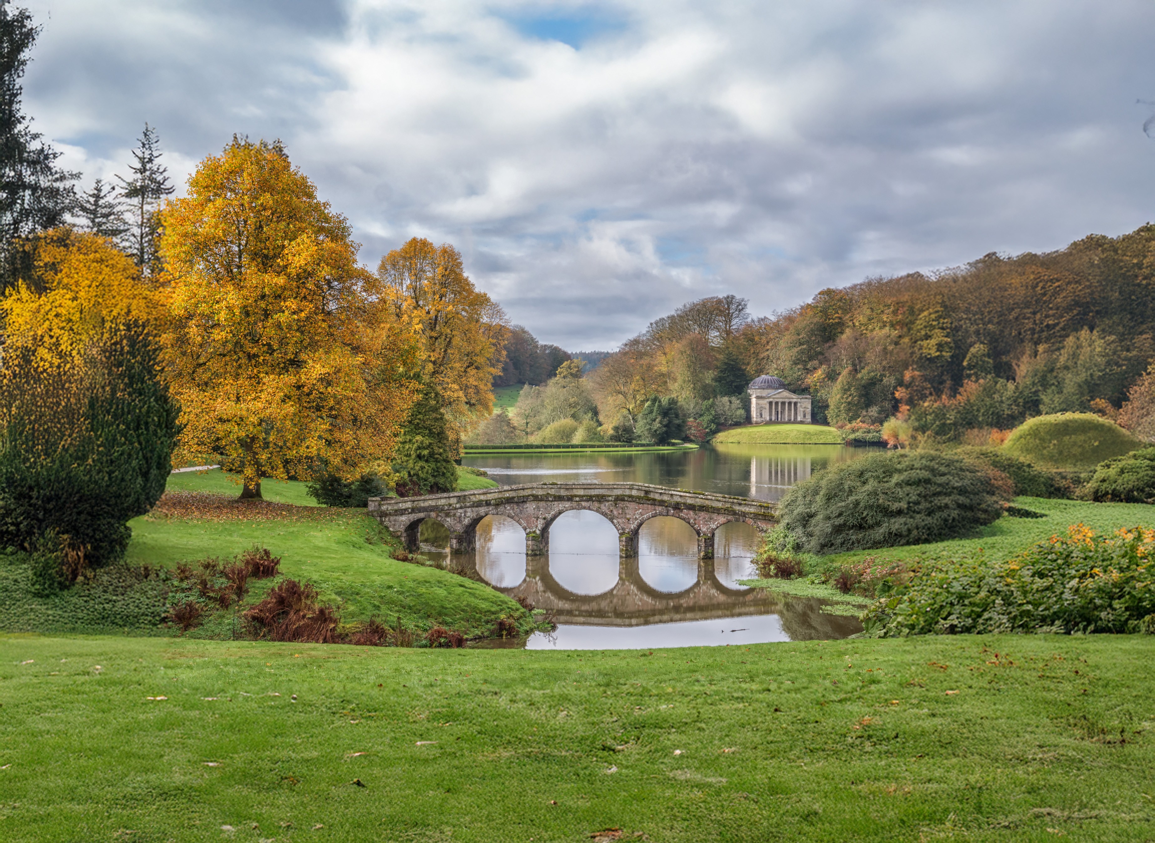 A stone bridge and classical temple at Stourhead Gardens, representing legacy, structure, and enduring continuity.