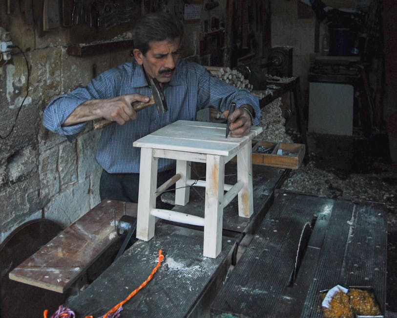 A carpenter skillfully crafting a wooden stool in his workshop using hand tools.