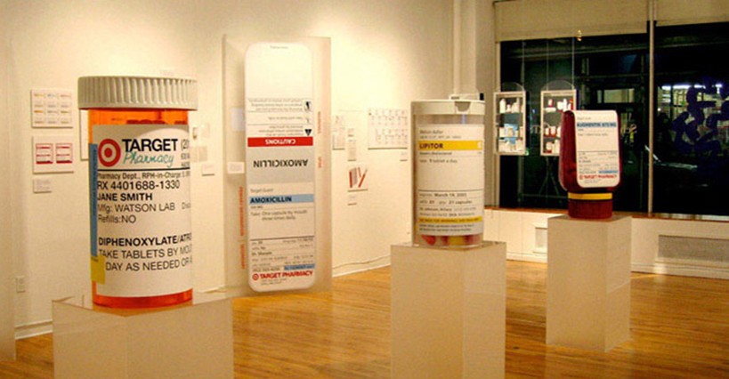 A photo of an art exhibition showing big pill bottles on pedestals.