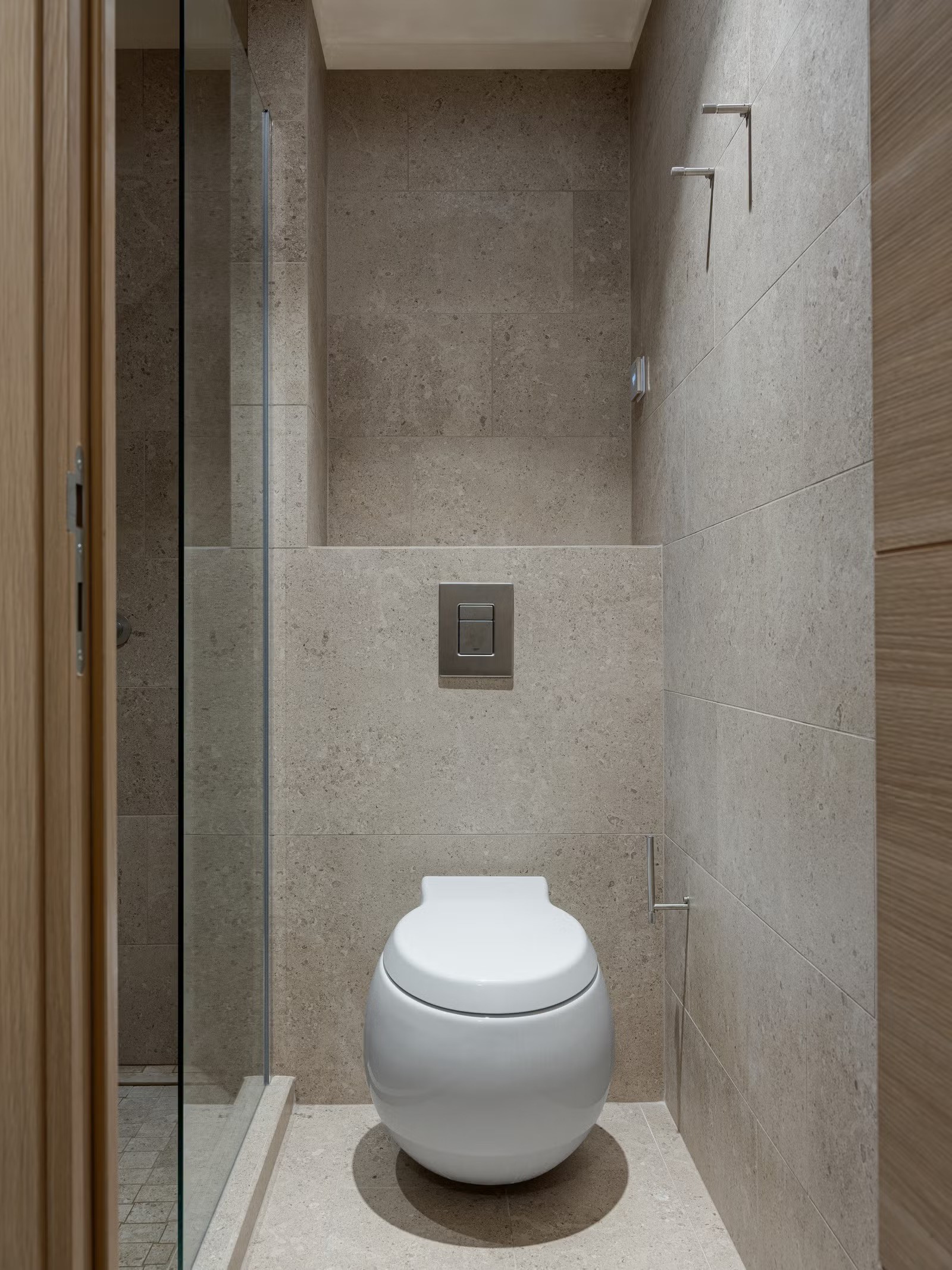 Espace toilettes minimaliste avec carrelage à effet pierre naturelle et niche de rangement intégrée.