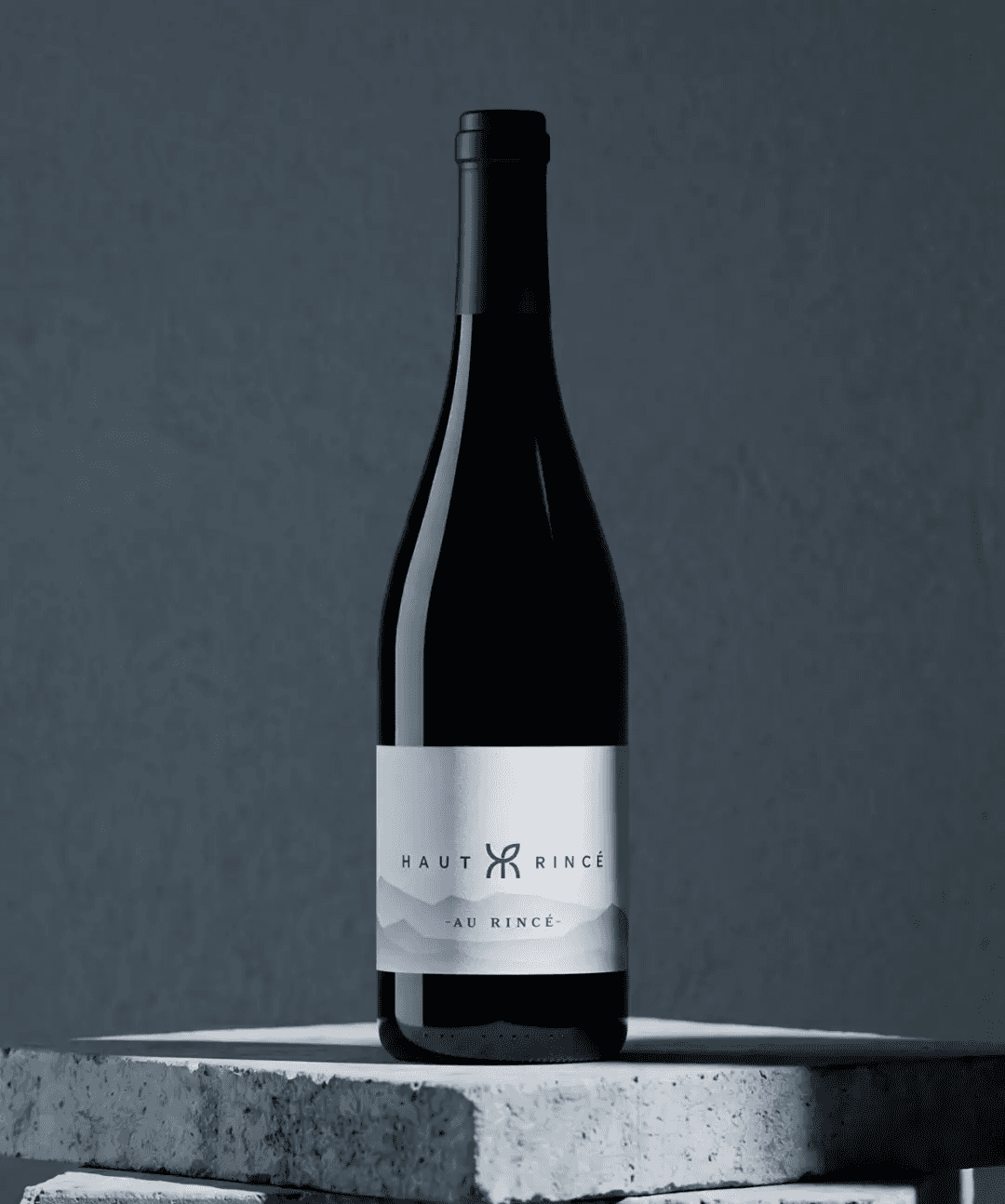 Une bouteille de vin rouge posé sur un bloc de pierre gris