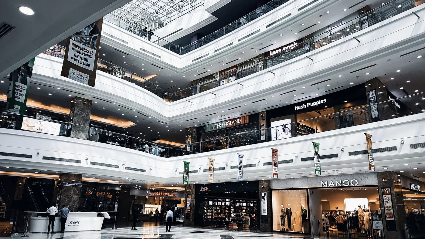 The atrium of a bright shopping mall, with shopfronts on several floors