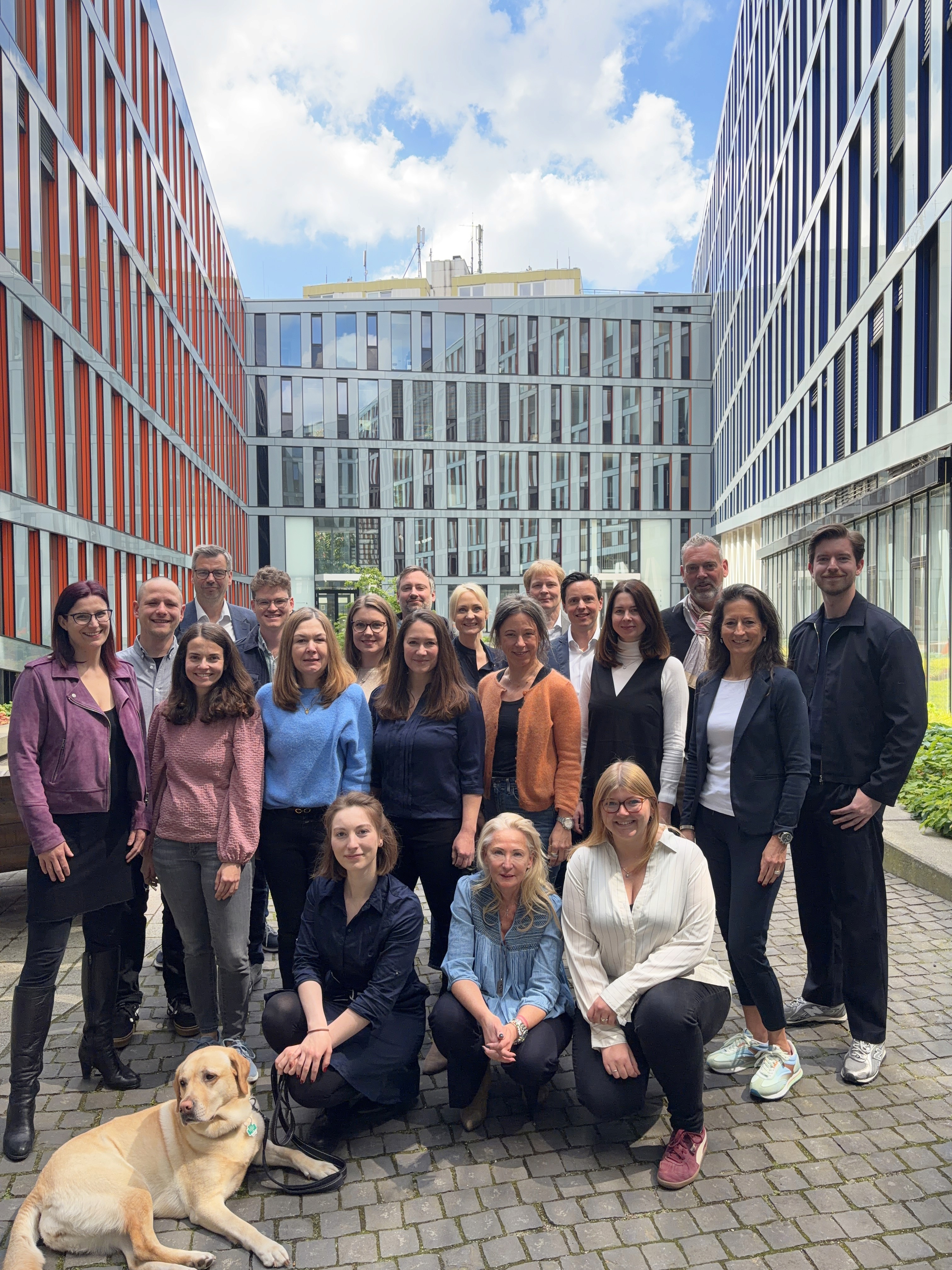 Das public imaging Team beim VIQ-Coaching mit deepvelop – Gruppenfoto mit 20 Personen und Hund vor modernem Bürogebäude