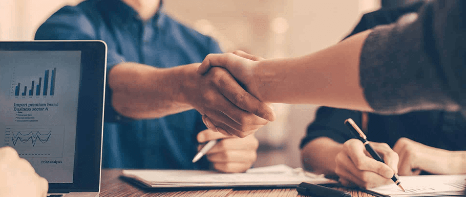 Two people shaking hands during a meeting in a conference room