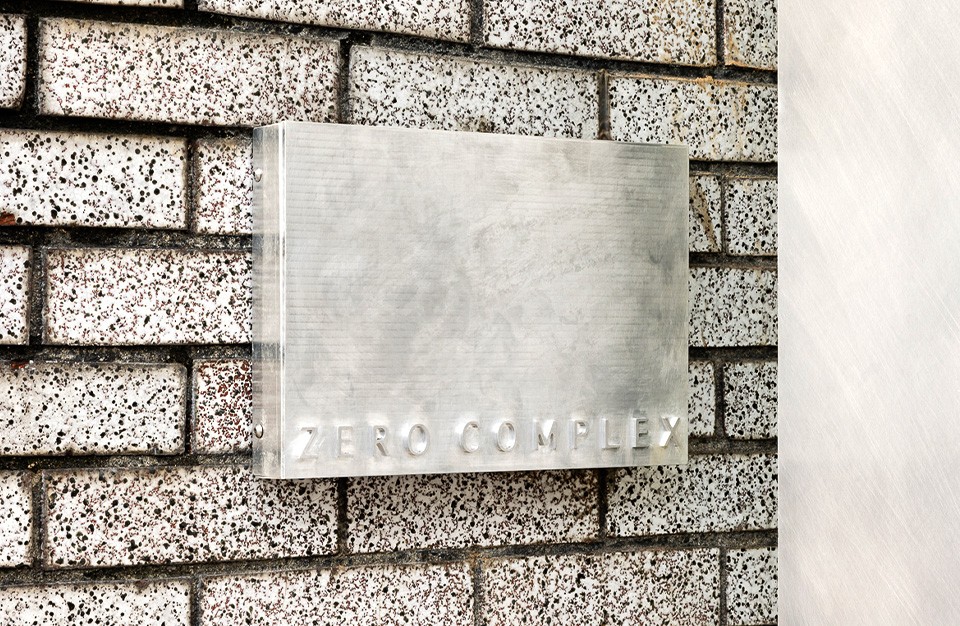 브러시드 메탈 질감의 간판이 벽돌 외벽에 부착된 모습