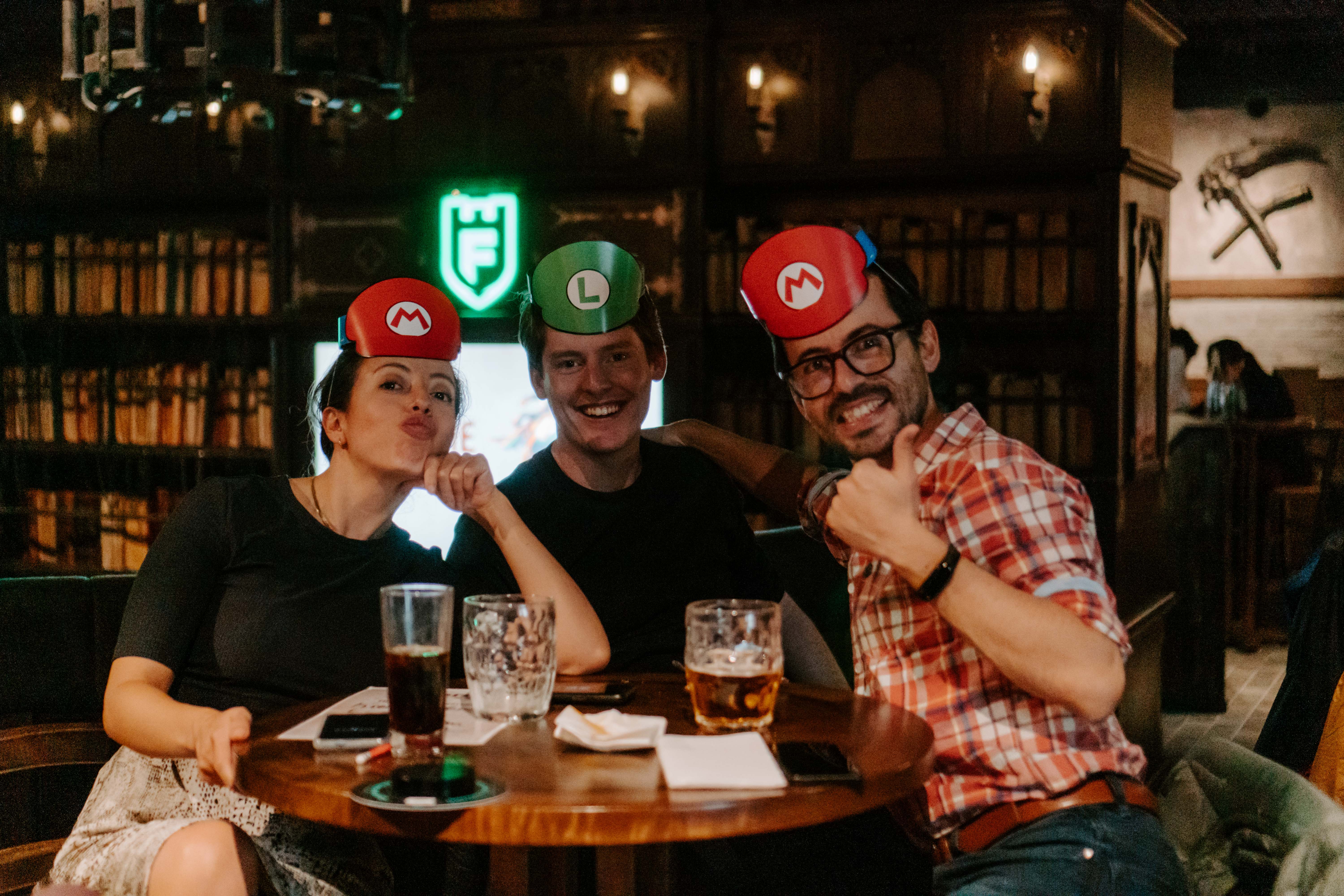 team of friends sitting at table playing trivia with mario and luigi hats on