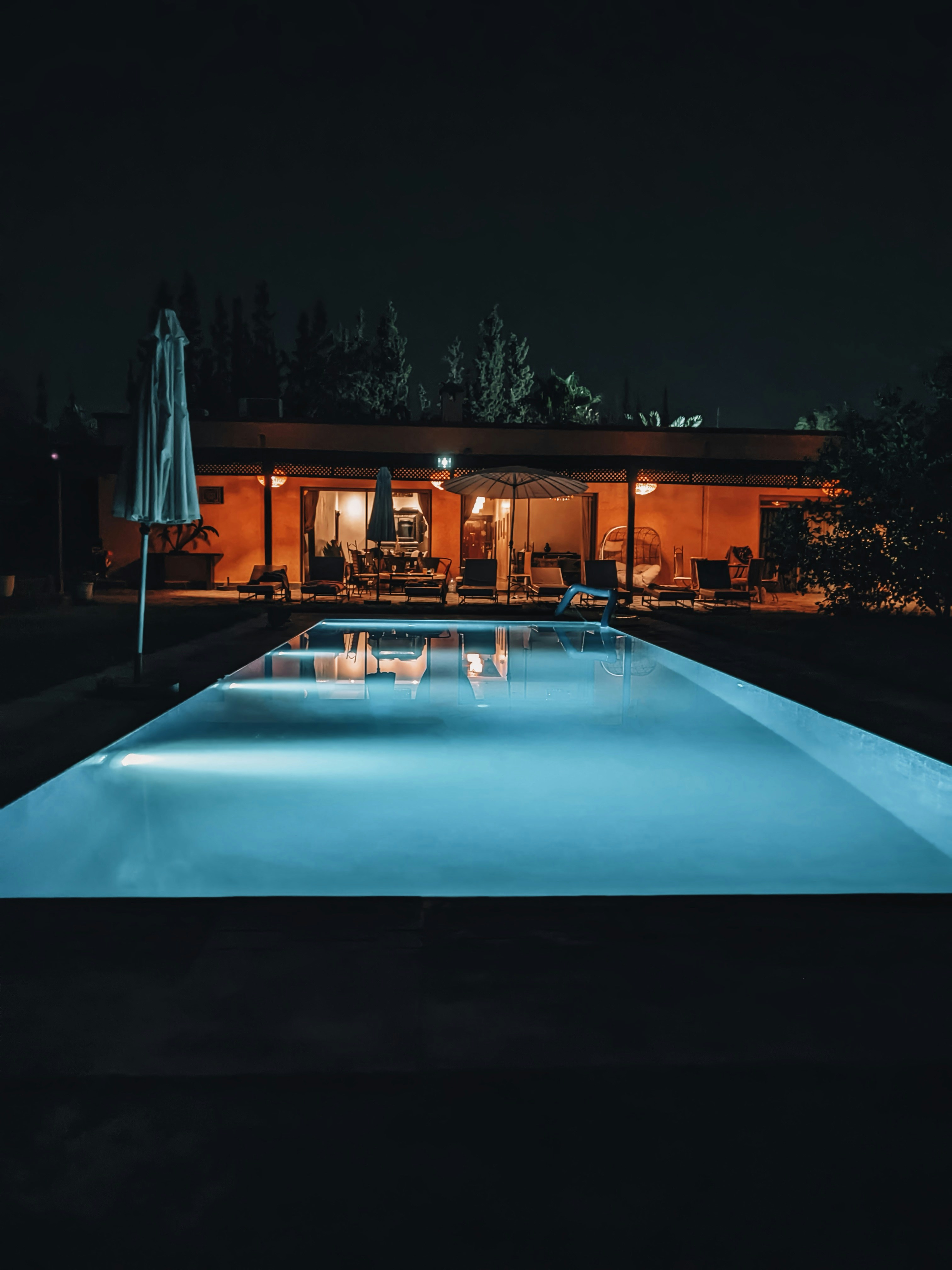 Illuminated swimming pool in front of a house at night