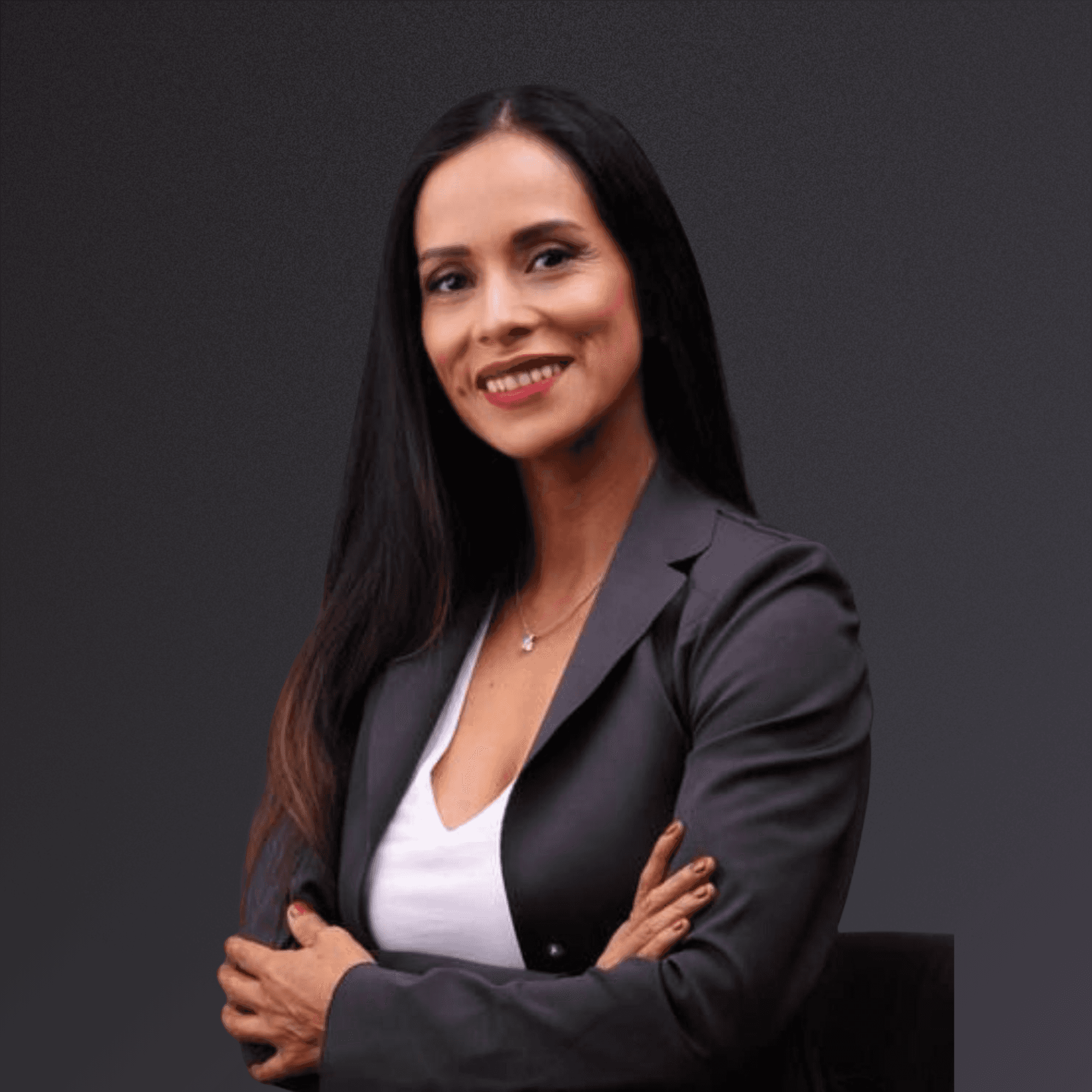 Woman with a short haircut smiling confidently, wearing a blazer and standing in warm natural light with modern architecture behind her.