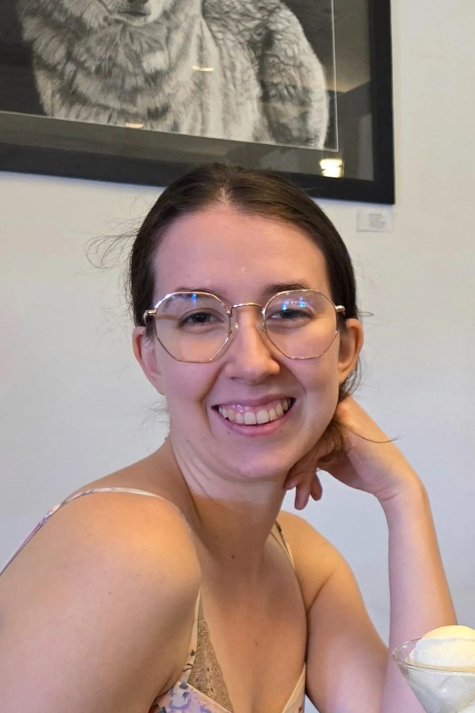 A couple in wedding attire shares a romantic kiss on a leafy path by a tranquil river.