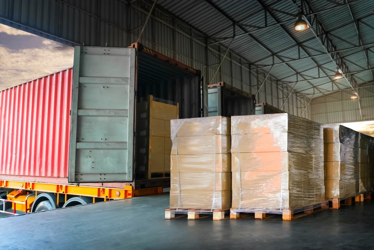 Truck loading safety with palletized cargo being staged at a warehouse loading dock before loading into a container truck