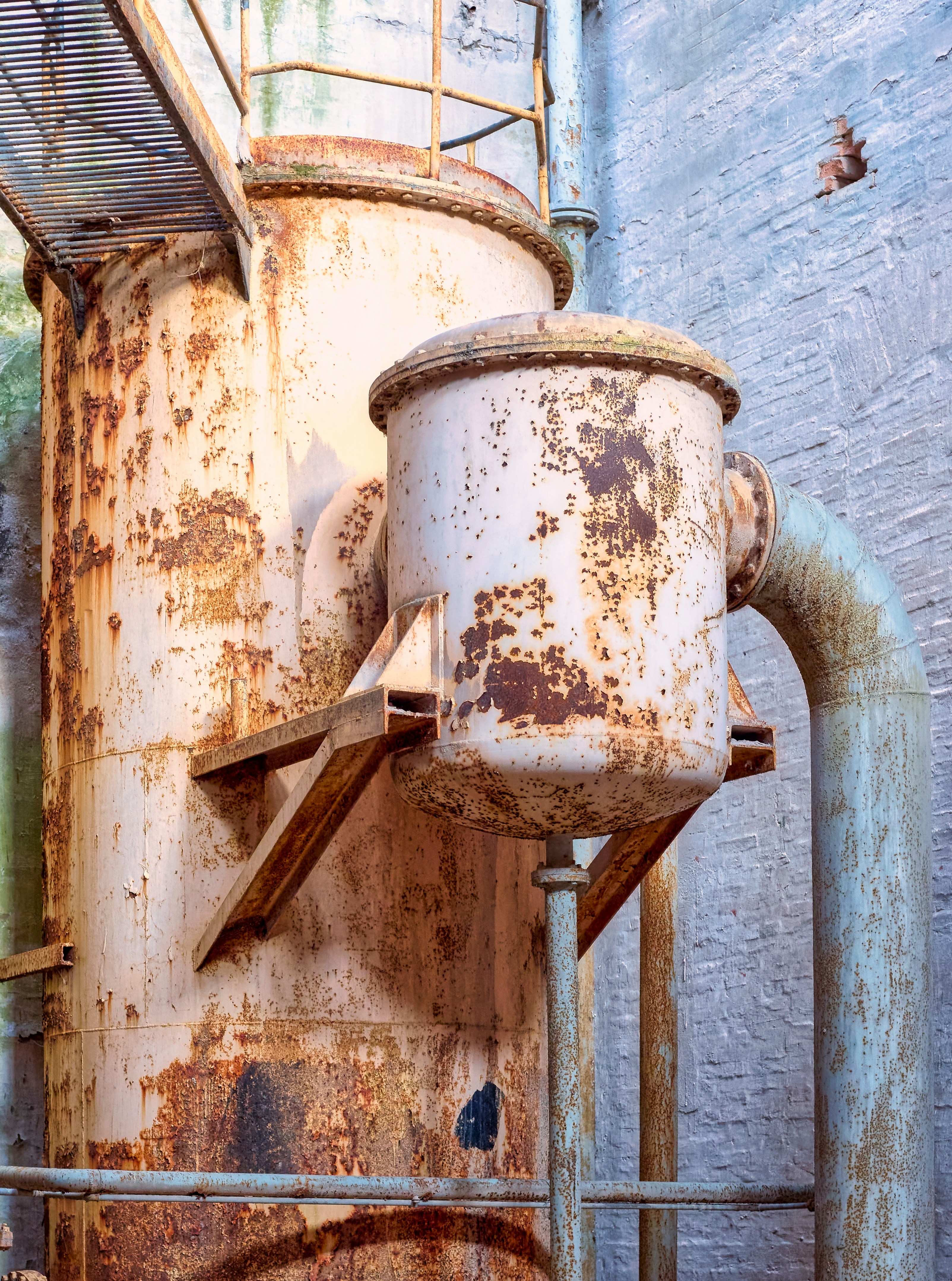 Rusted industrial machinery with pipes and ladder