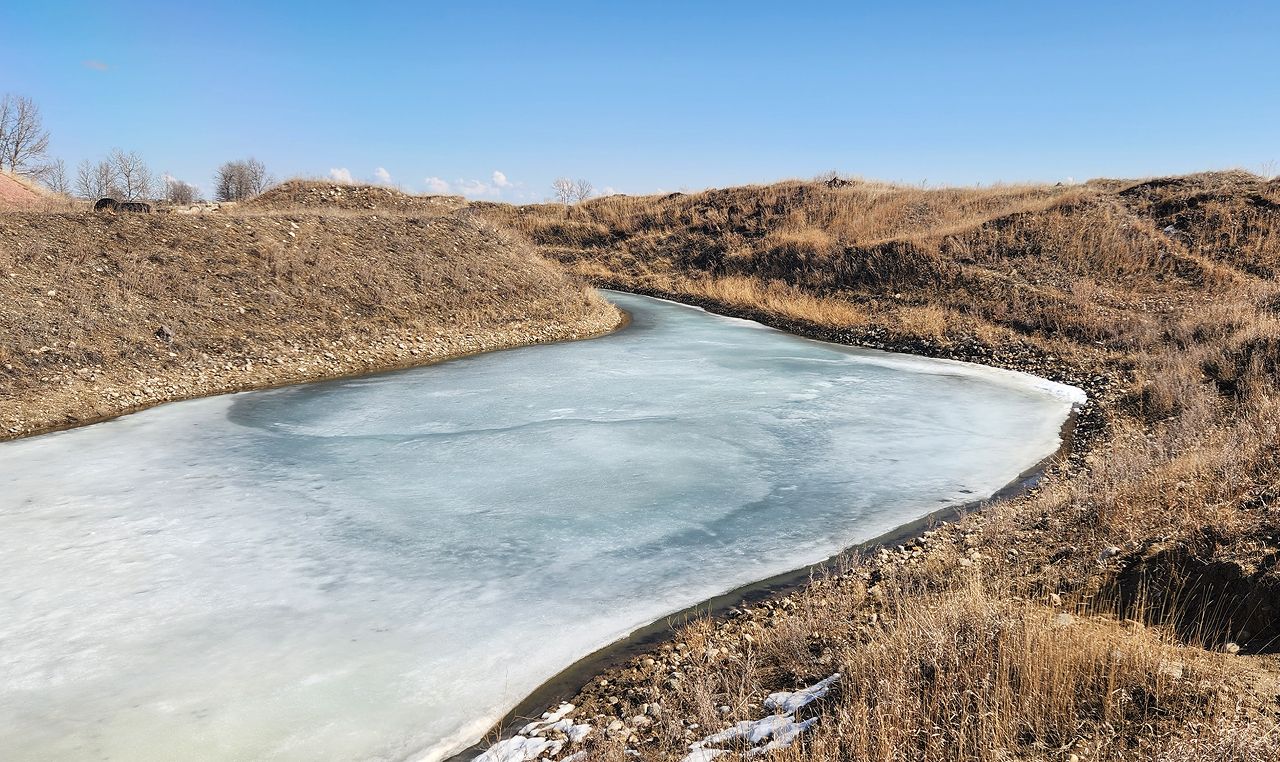 Frozen pond in legacy gravel pit requiring stormwater management planning near Irricana Alberta