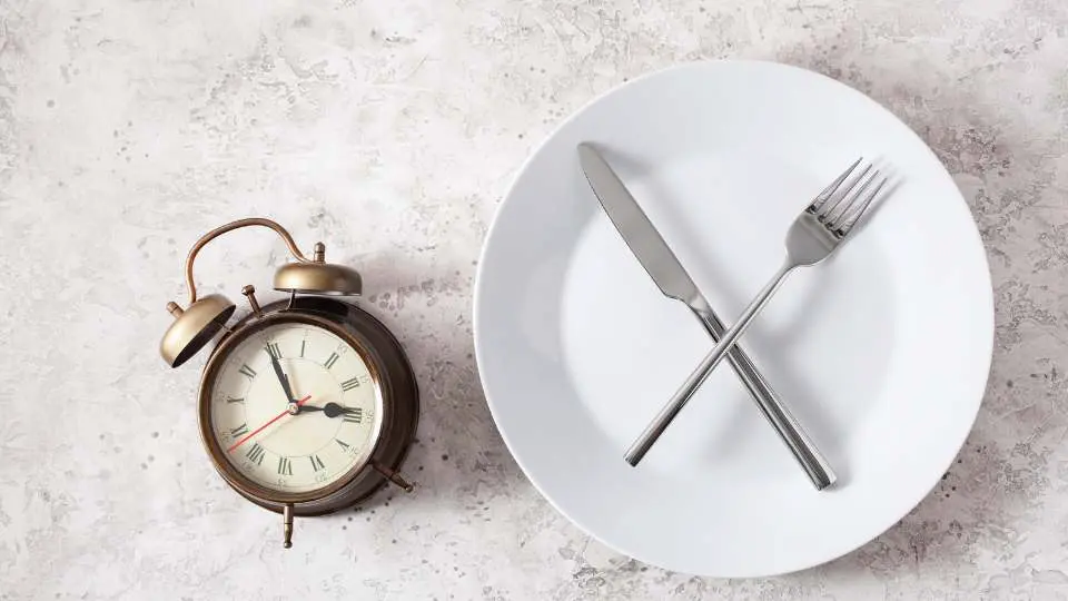 alarm clock and empty plate with knife and fork