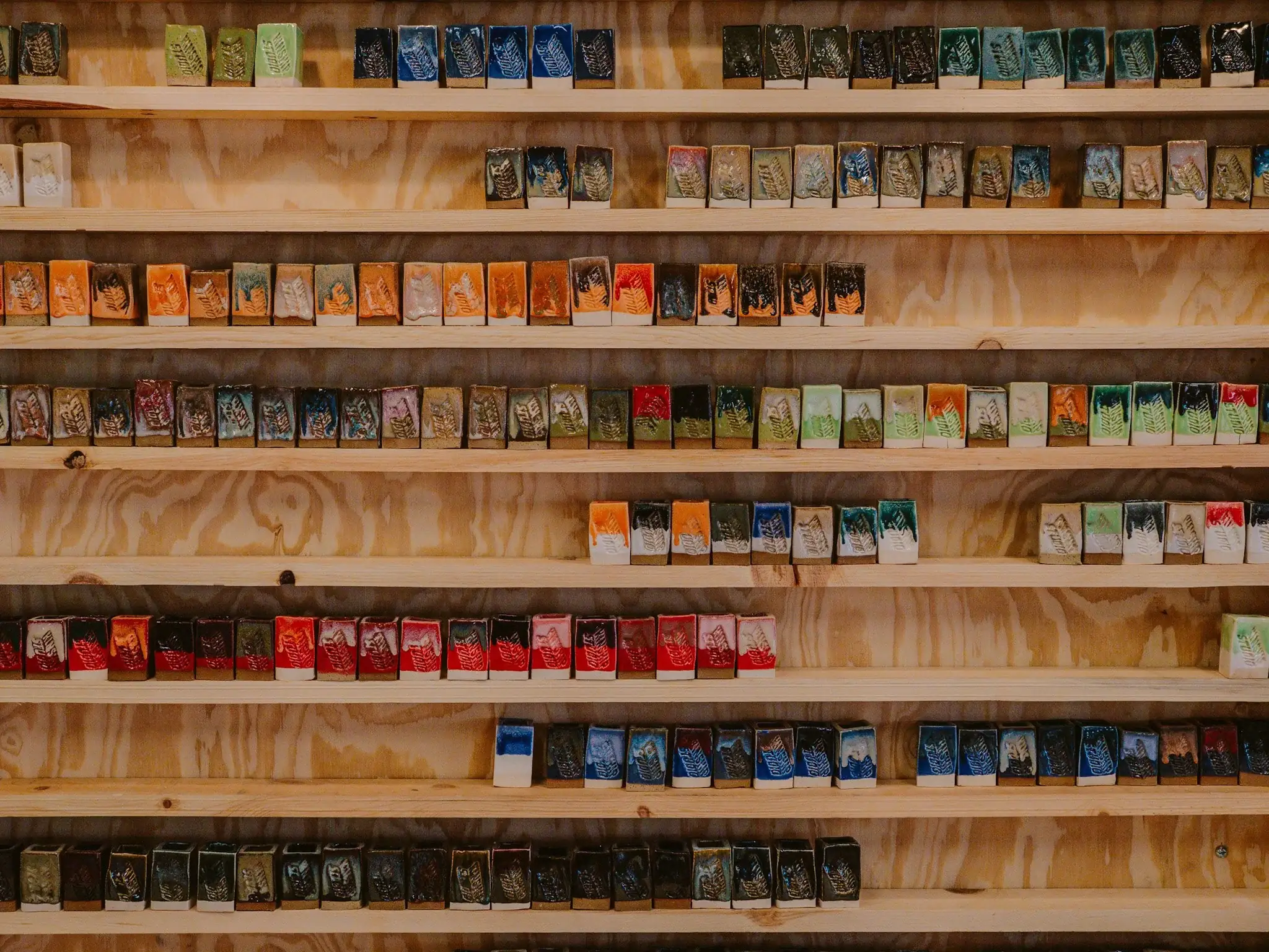 Wall of glaze test tiles showing Kinship's dipping glaze combinations