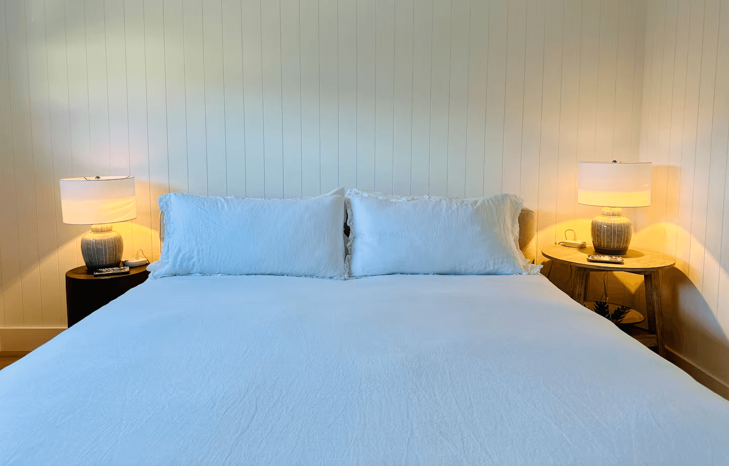 Primary bedroom in Soul & Sea condo 8 with white linens and warm bedside lighting