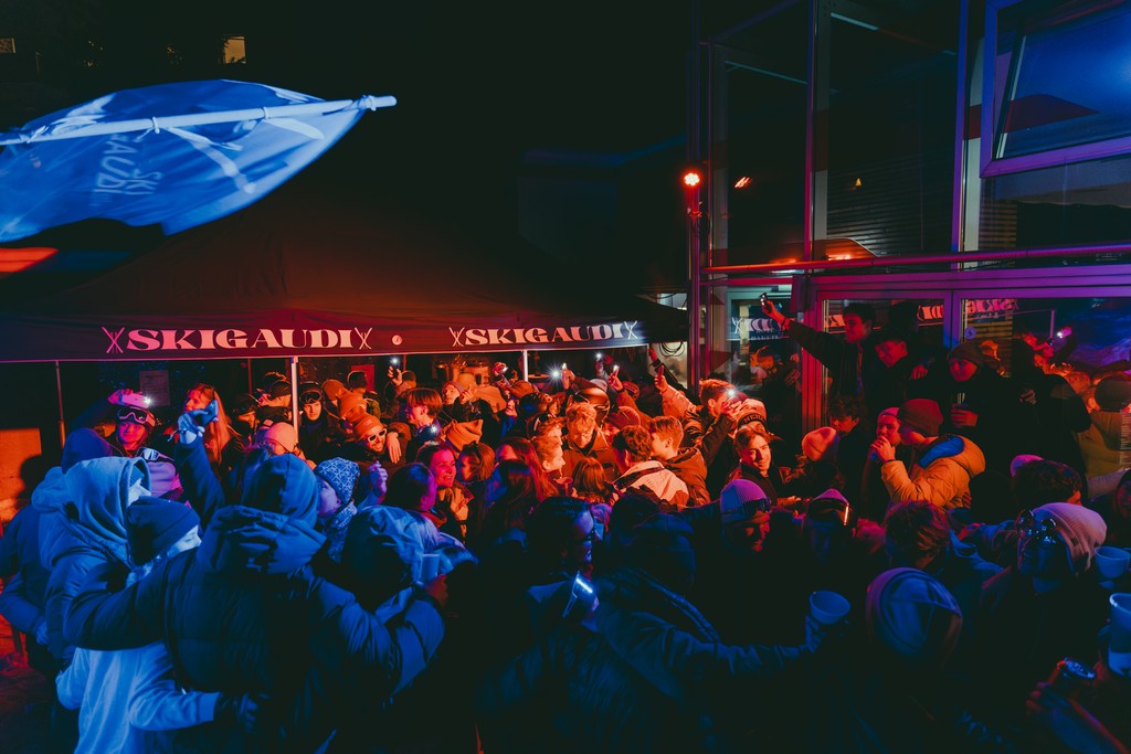 Nighttime outdoor party with people dancing and enjoying music under colorful lights.