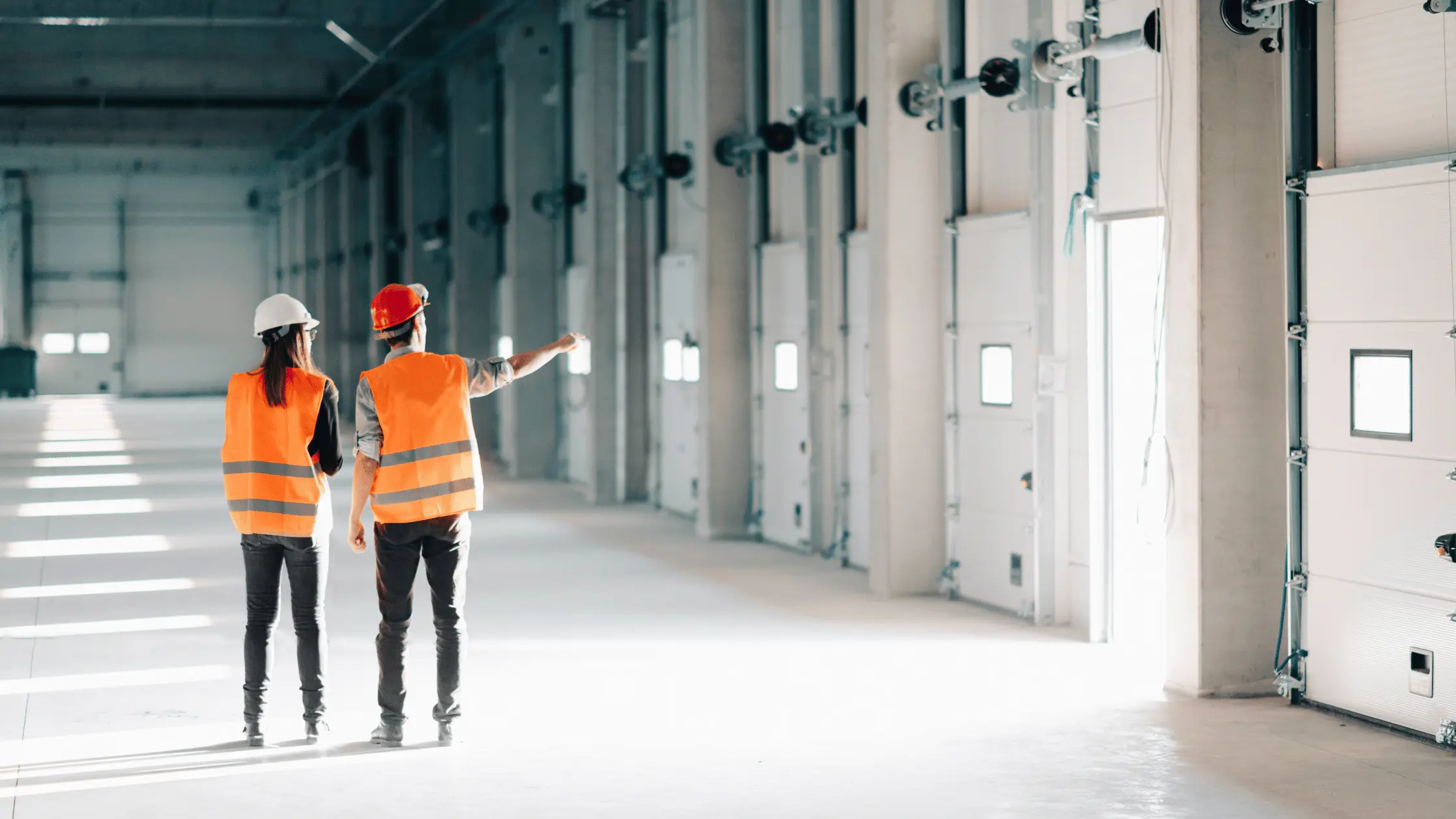 A man stands while two people sit at a table in an office setting, smiling and engaged in conversation. The mood is friendly and collaborative.