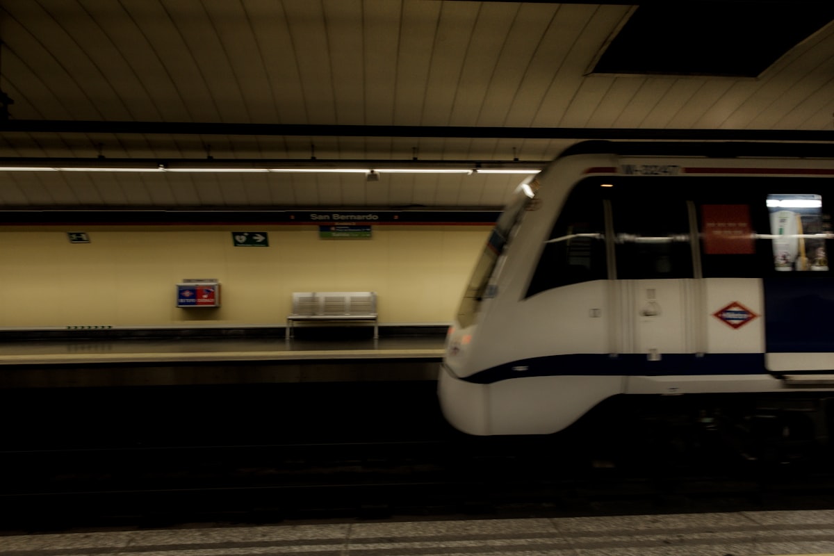 A white commuter train pulling into a busy Madrid station platform, the heart of getting around Spain