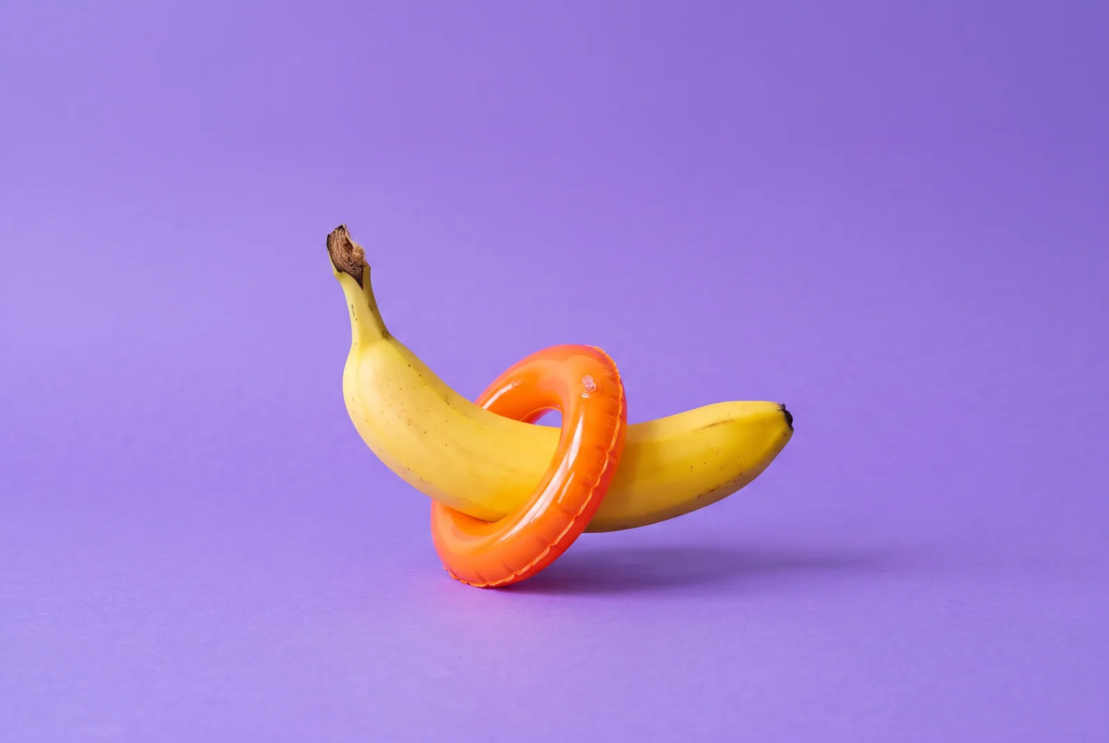 Relapse prevention plan concept: a ripe banana wearing a tiny orange inflatable swim ring on a lilac backdrop