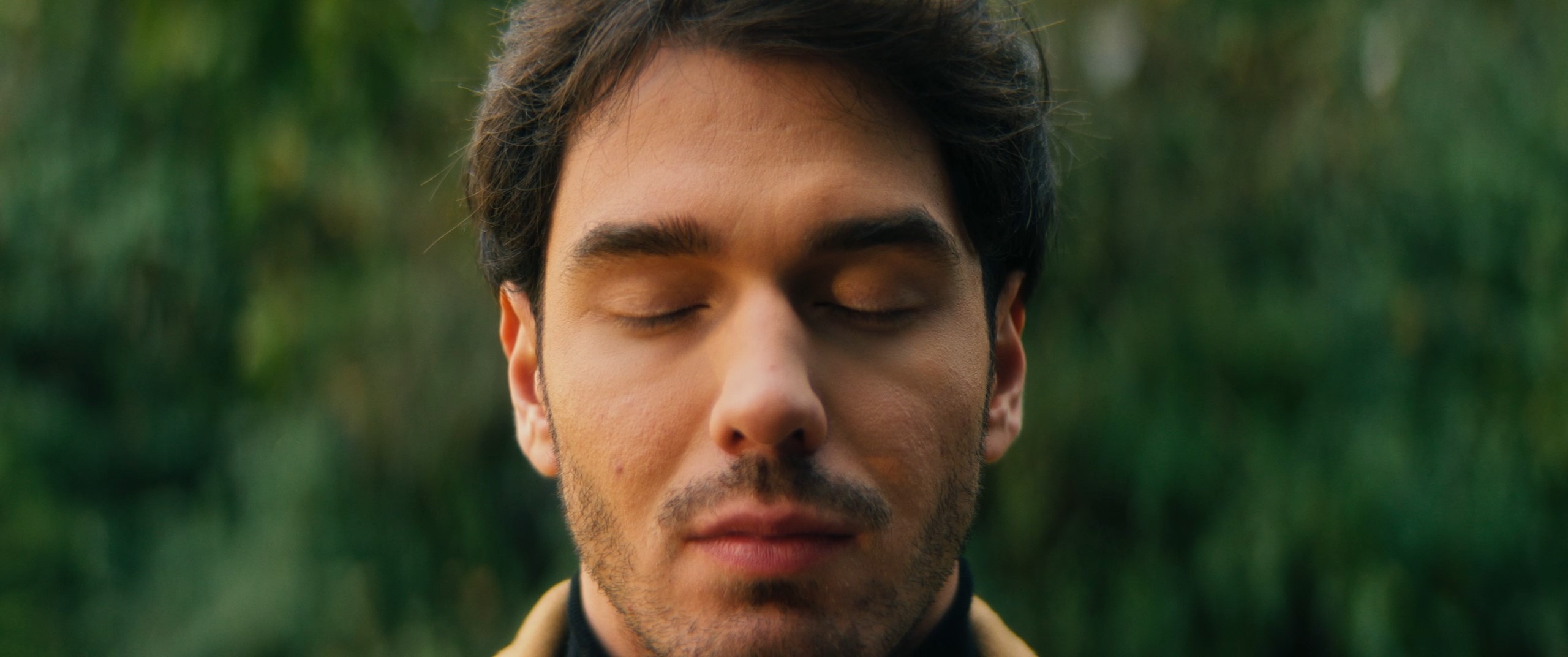 a man sits in a park and has his eyes closed