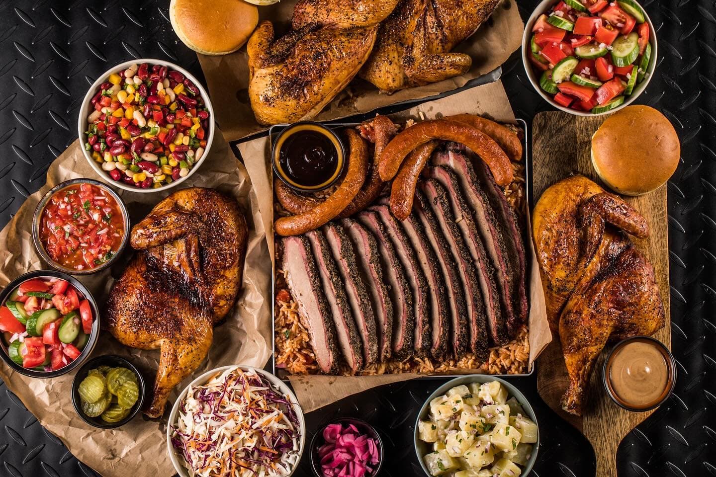 BBQ restaurant dubai showcasing a barbecue box platter with sliced brisket, chicken, and a selection of classic barbecue sides.