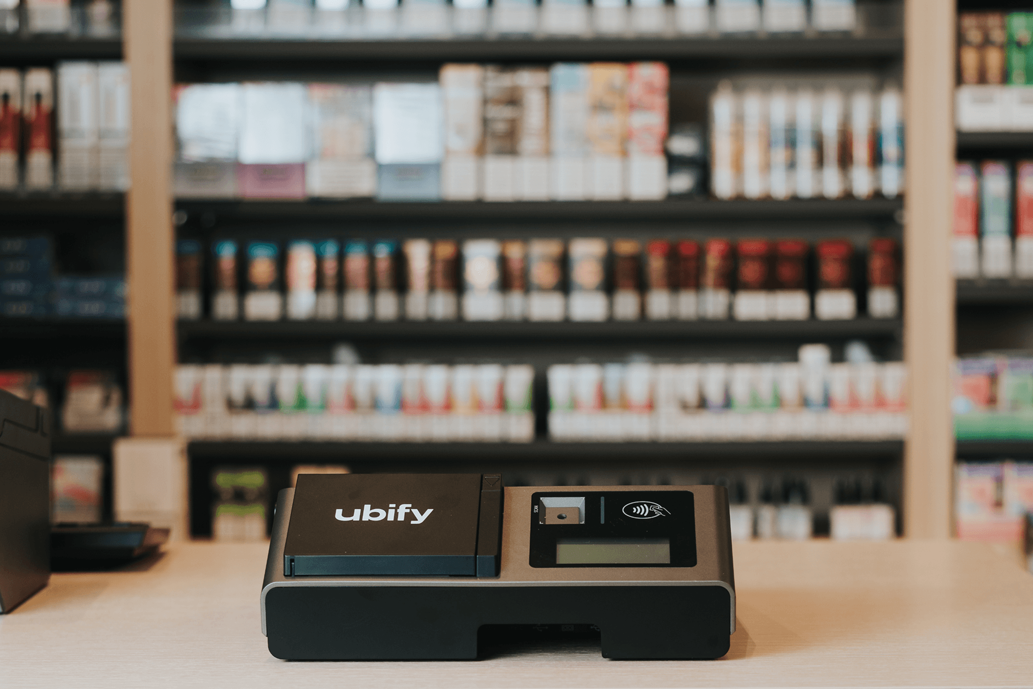 Cassa Ubify su bancone di negozio con scaffali pieni di prodotti sullo sfondo.