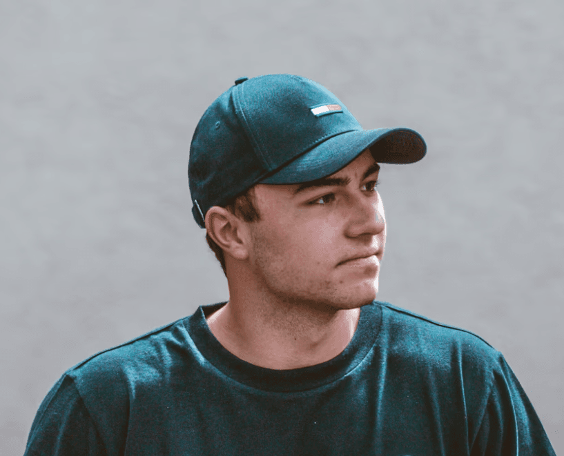 a young man wearing glasses standing in front of a mountain
