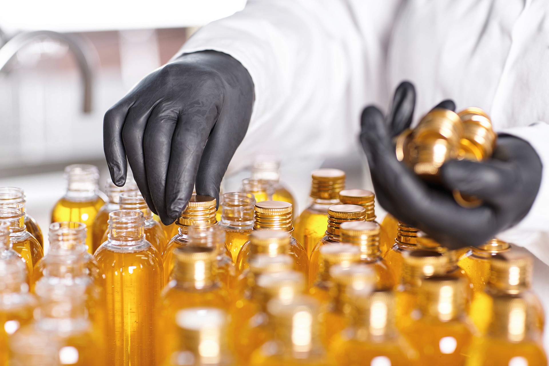 Production of cosmetics, including glass jars with golden liquids, emphasizing care in the manufacturing of beauty products.