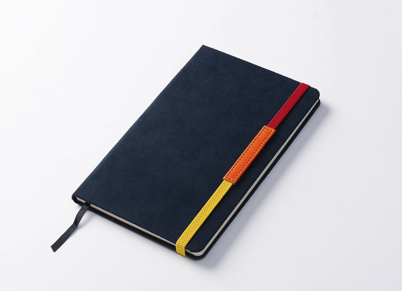 Angled view of closed blue notebook with tricolor elastic band.